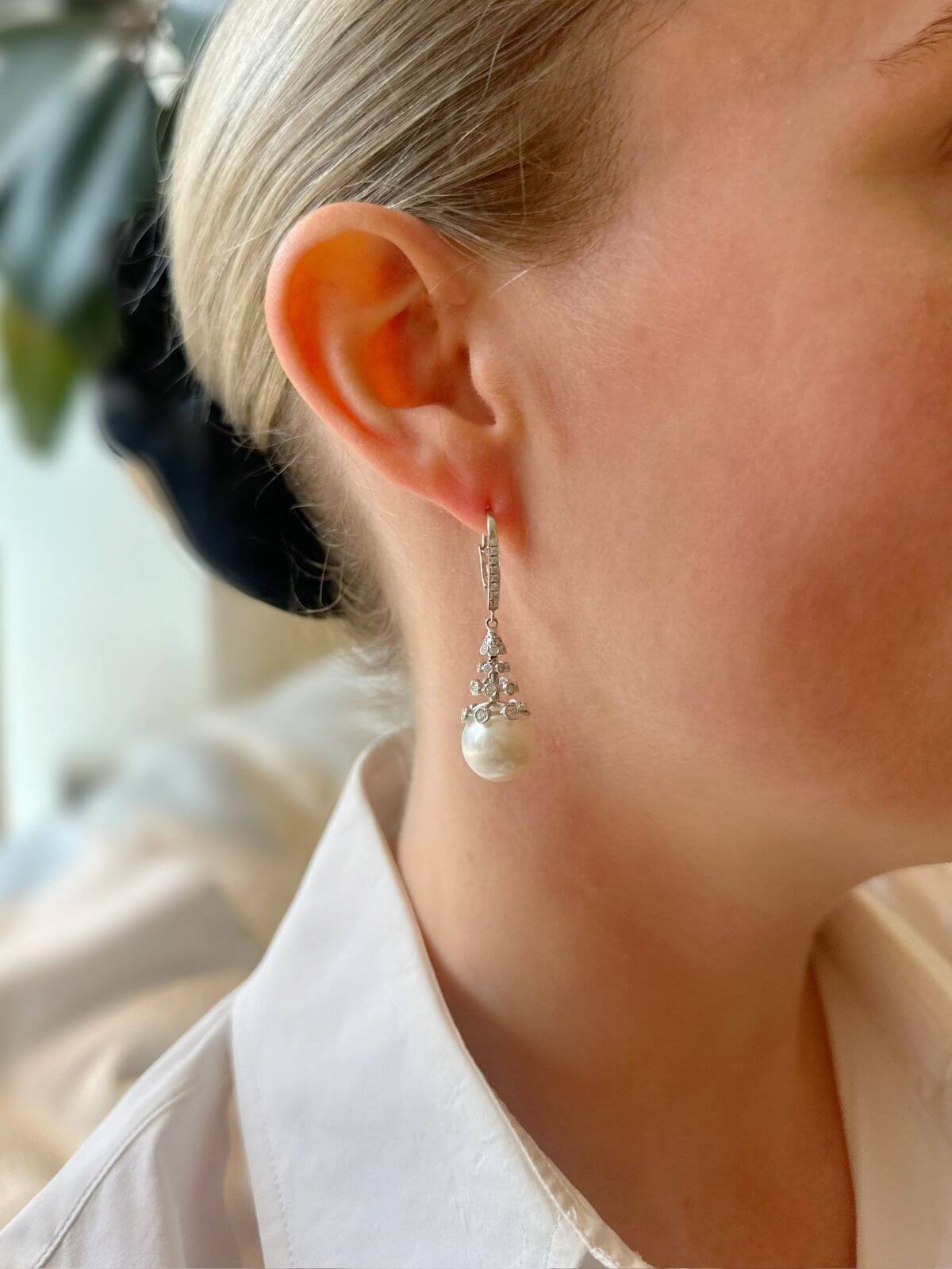 Close-up of a person wearing a pearl earring with a blurred background