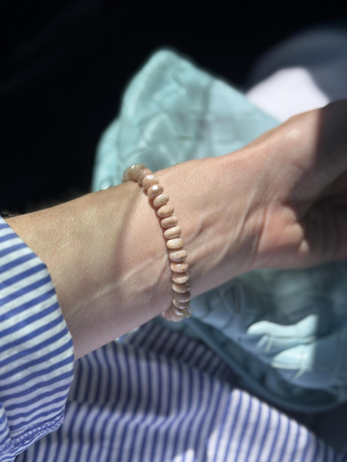Louise Row Studio featuring Sydney Evan pink bead bracelet on wrist with striped shirt and bag.