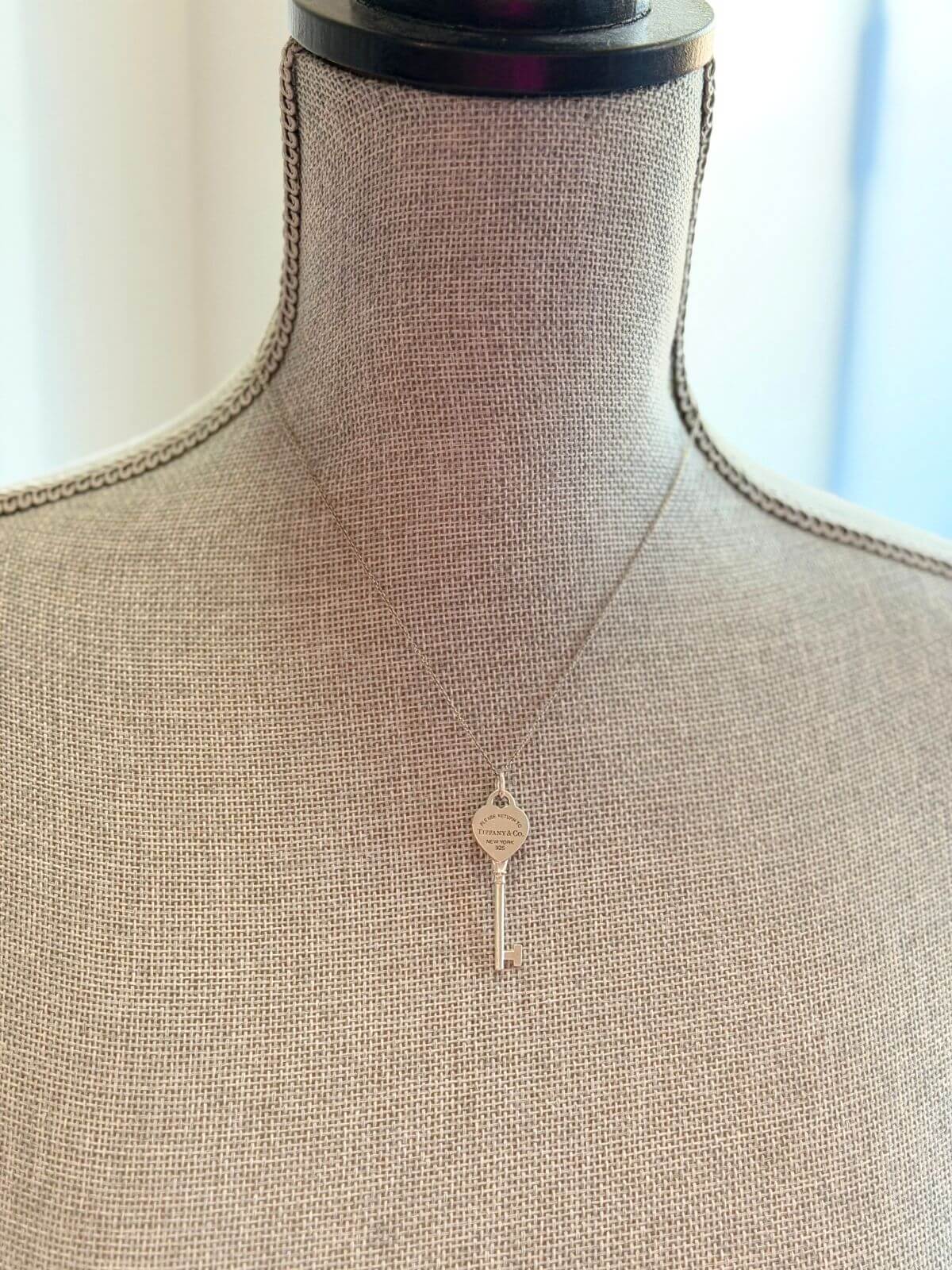 Louise Row featuring Tiffany & Co Heart Key Pendant in silver on grey mannequin