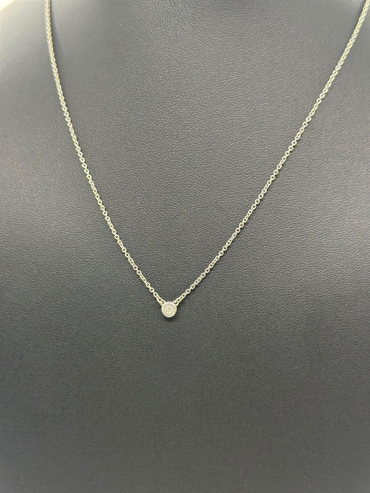 Silver Tiffany & Co solitaire diamond pendant on black fixture.