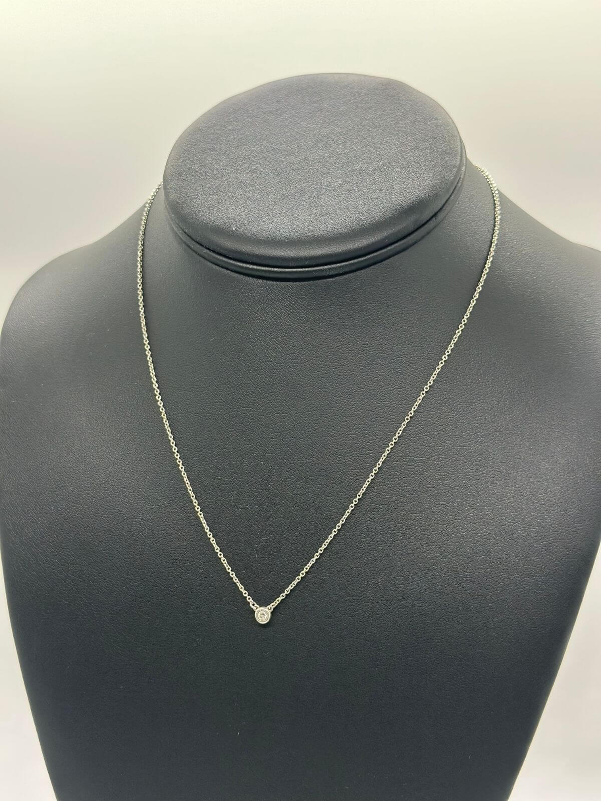 Silver Tiffany & Co solitaire diamond pendant on black fixture.