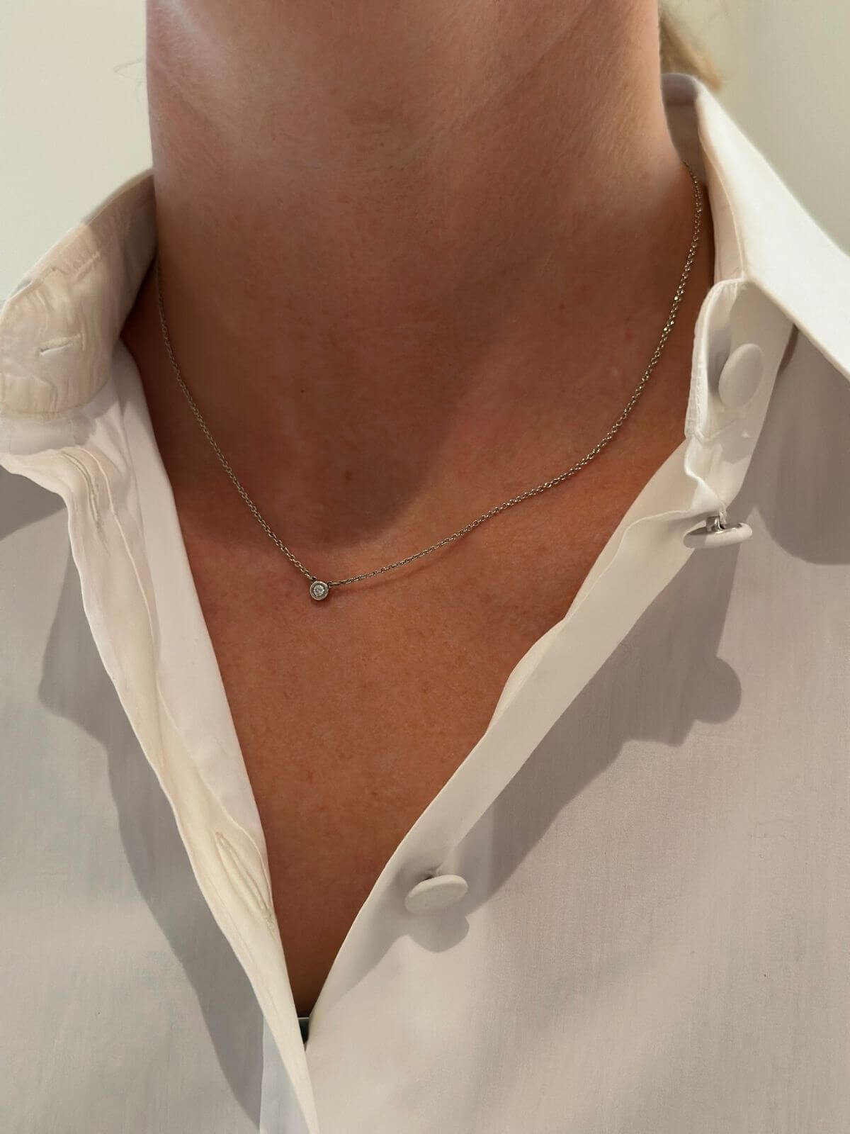 Model wearing a Tiffany & Co silver diamond pendant.