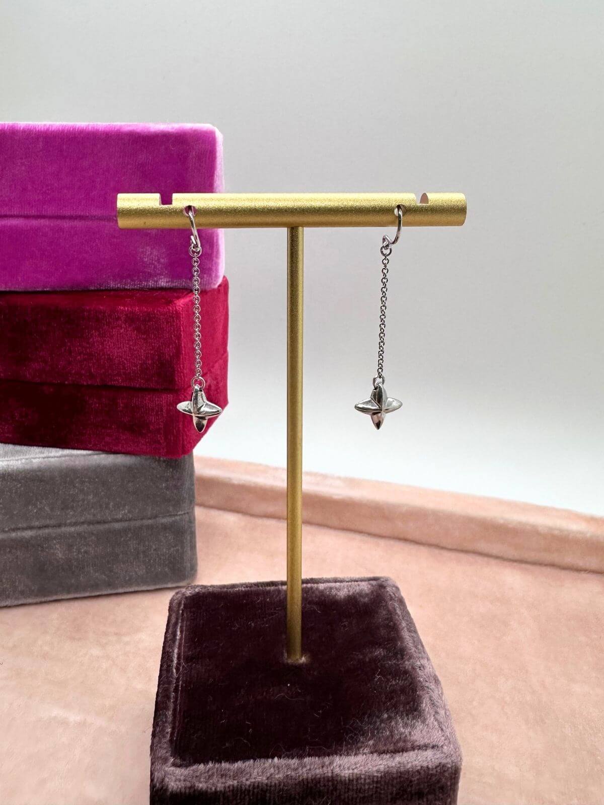 Tiffany Silver star earrings on stand on a gray surface