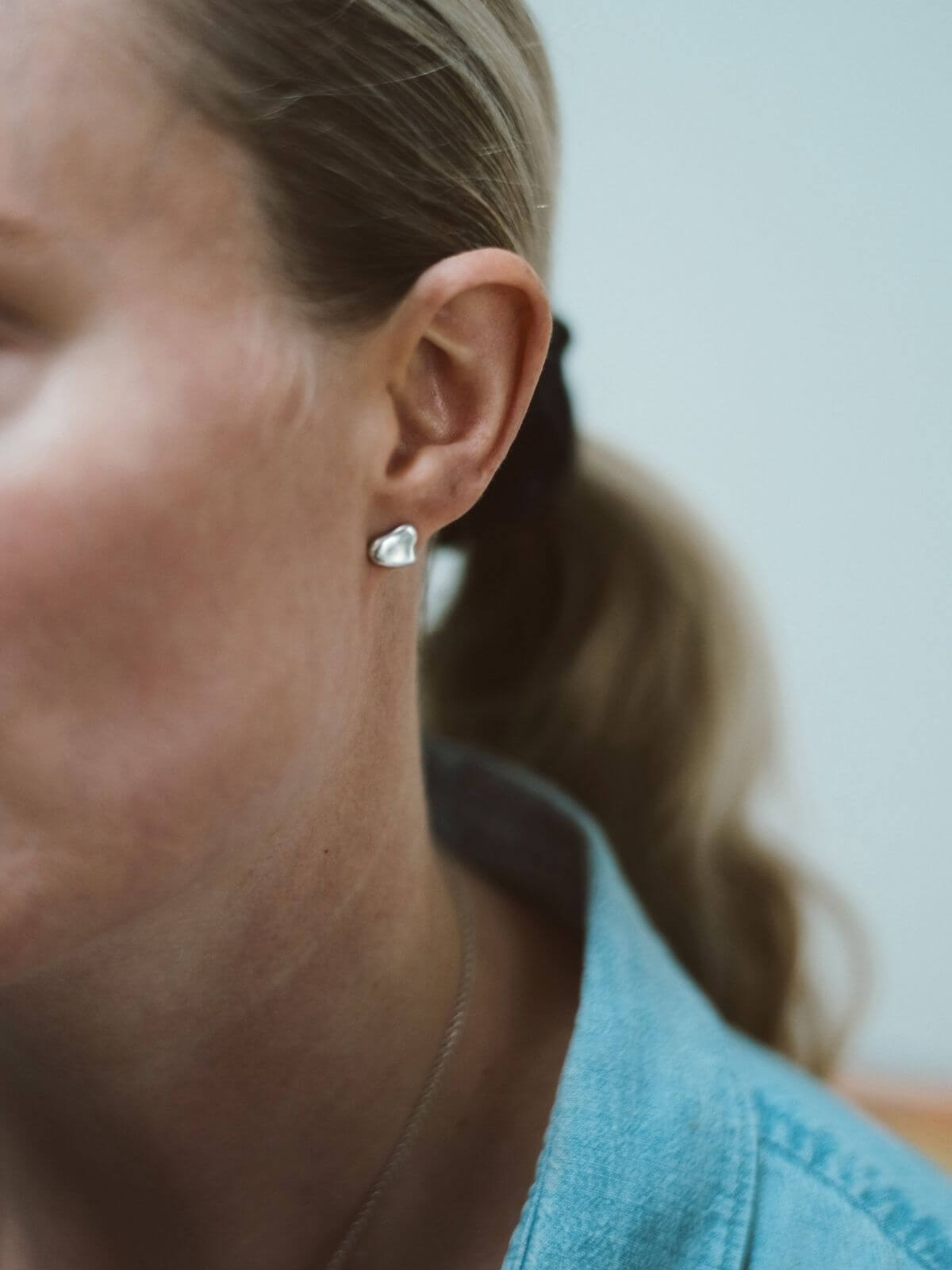 Close-up of a person wearing a heart-shaped earring with a blurred background