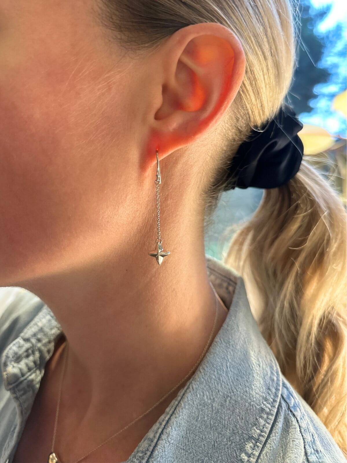 Close-up of a person wearing a silver earring with a star design.