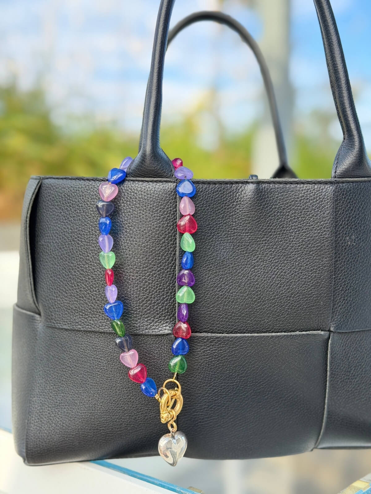 Louise Row featuring Timeless Pearly glass heart necklace on pink tray on bag