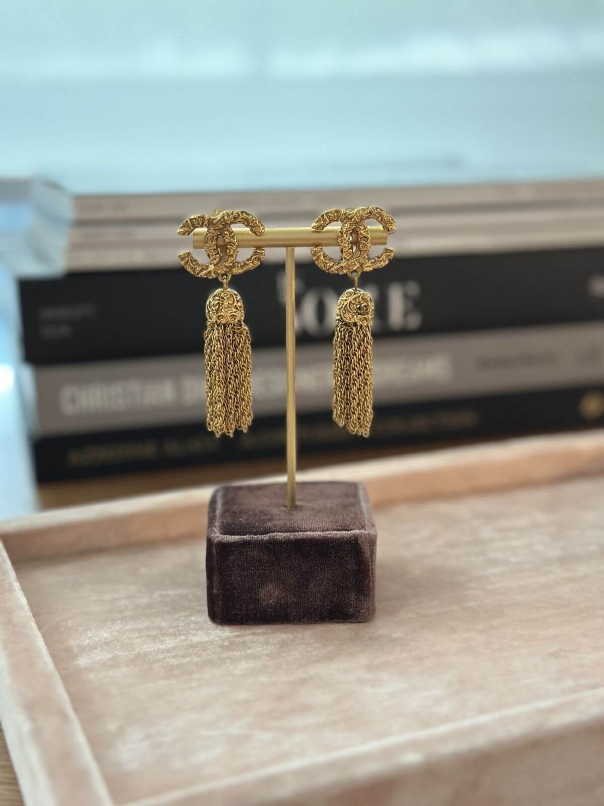 Gold tassel earrings on a stand with a blurred background