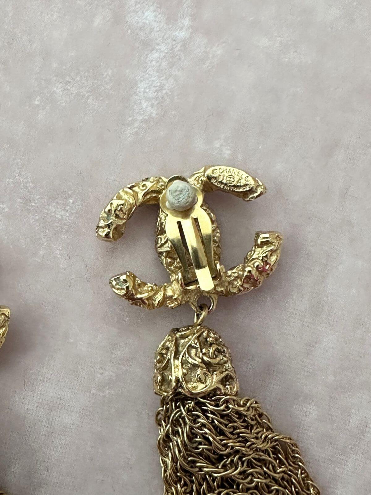 Gold earring with tassel on a light pink background