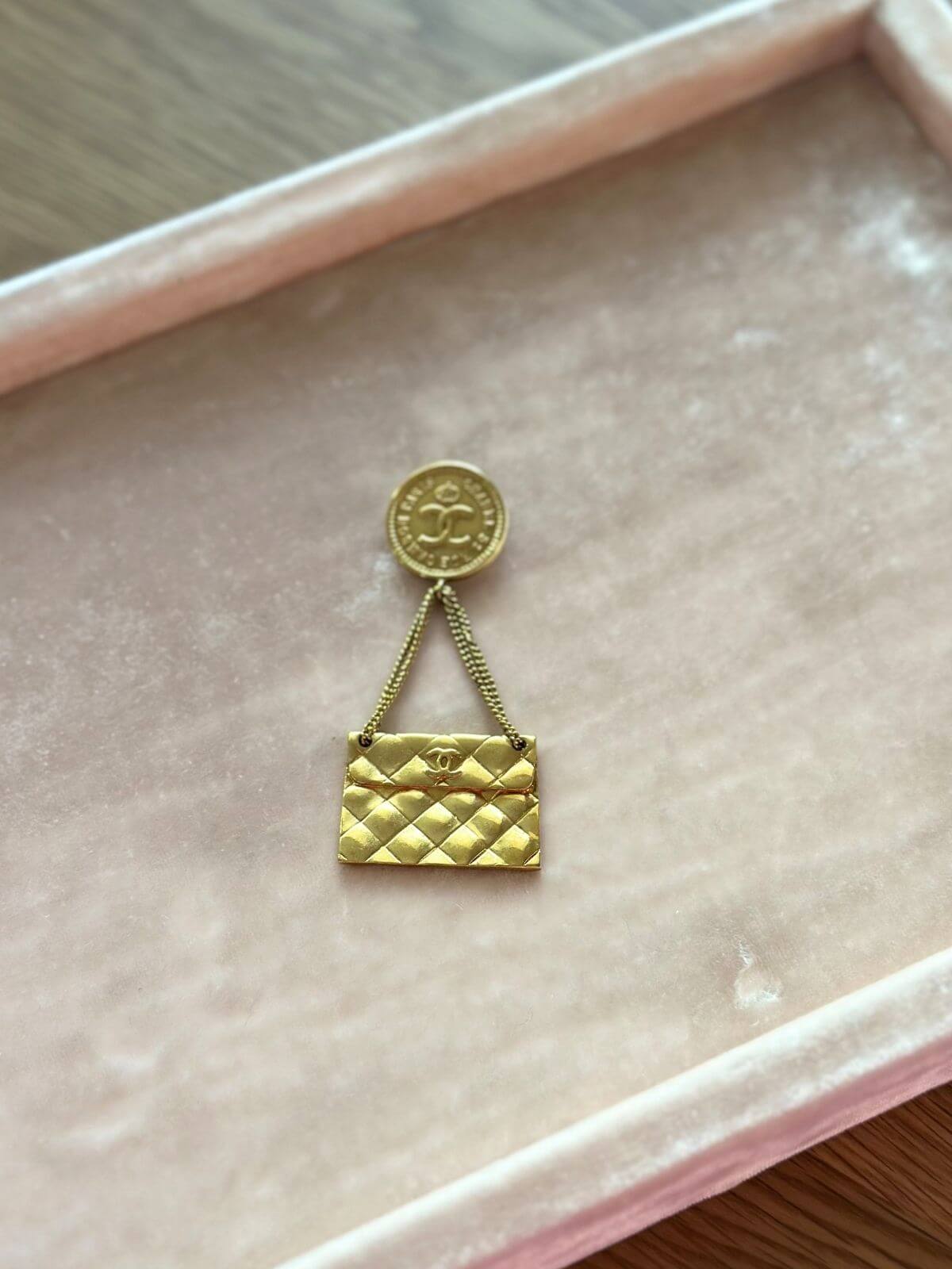 Chanel Gold brooch shaped like a quilted bag on a pink cushion