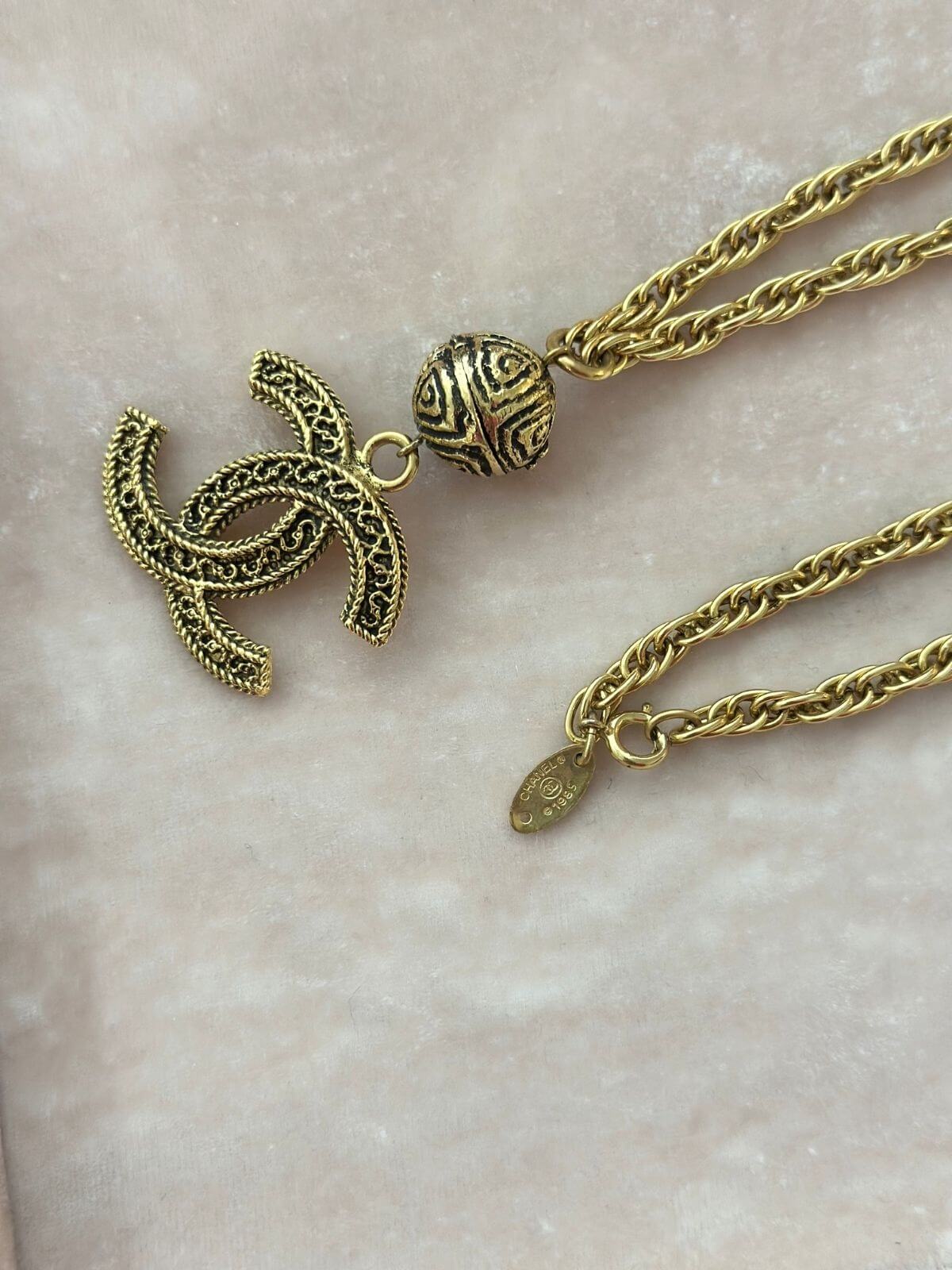 Gold necklace with turtle pendant on a light marble background