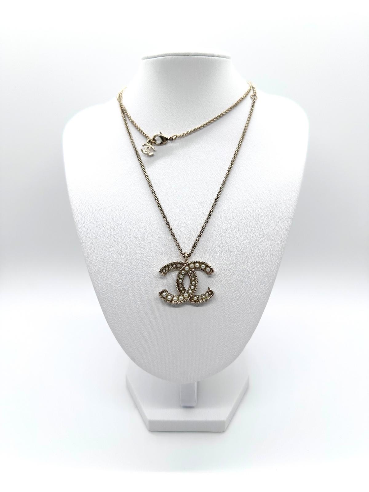 Chanel gold and pearl necklace on white bust form.