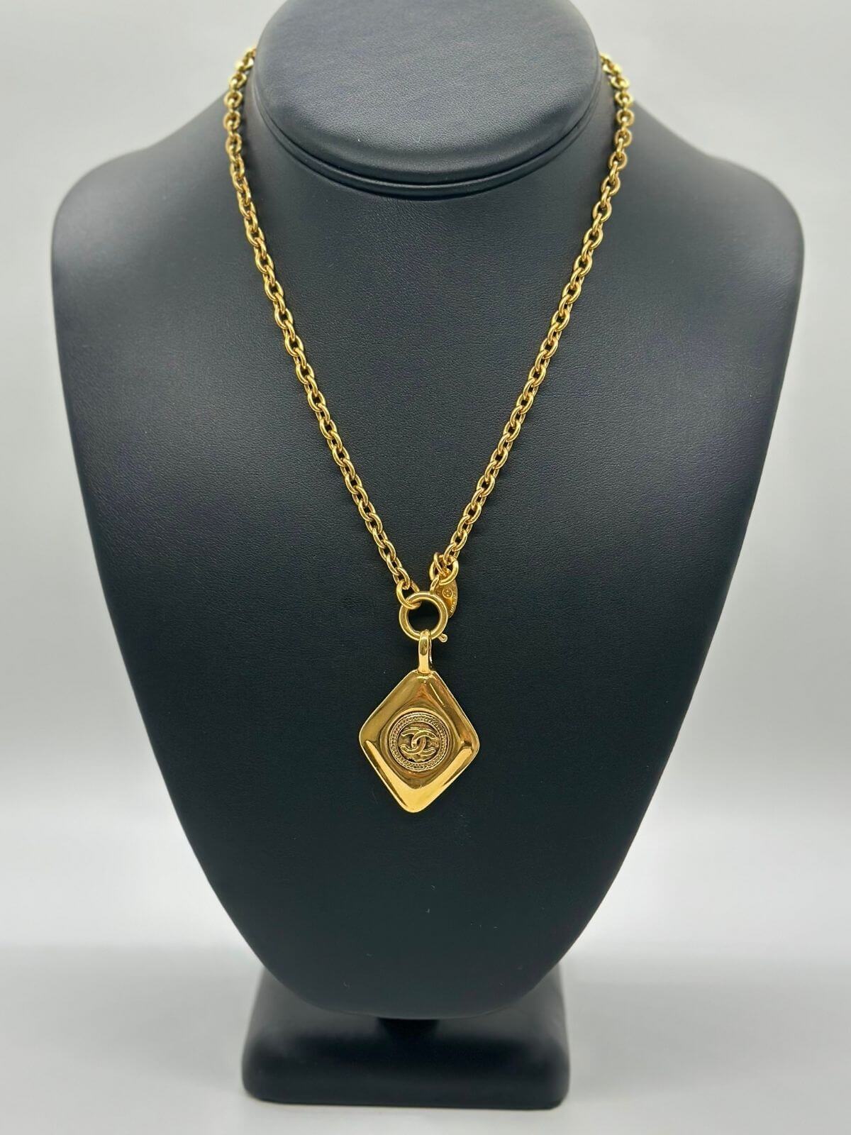 Gold diamond shared Chanel necklace on black neck form.
