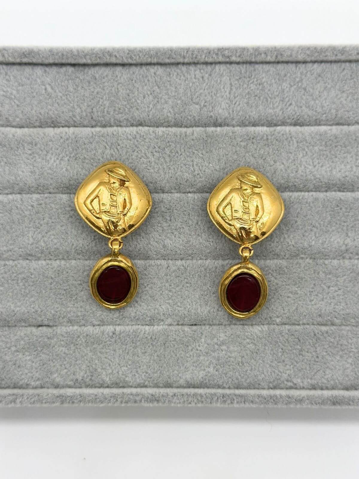Chanel gold and red Gripoix earring on grey background.