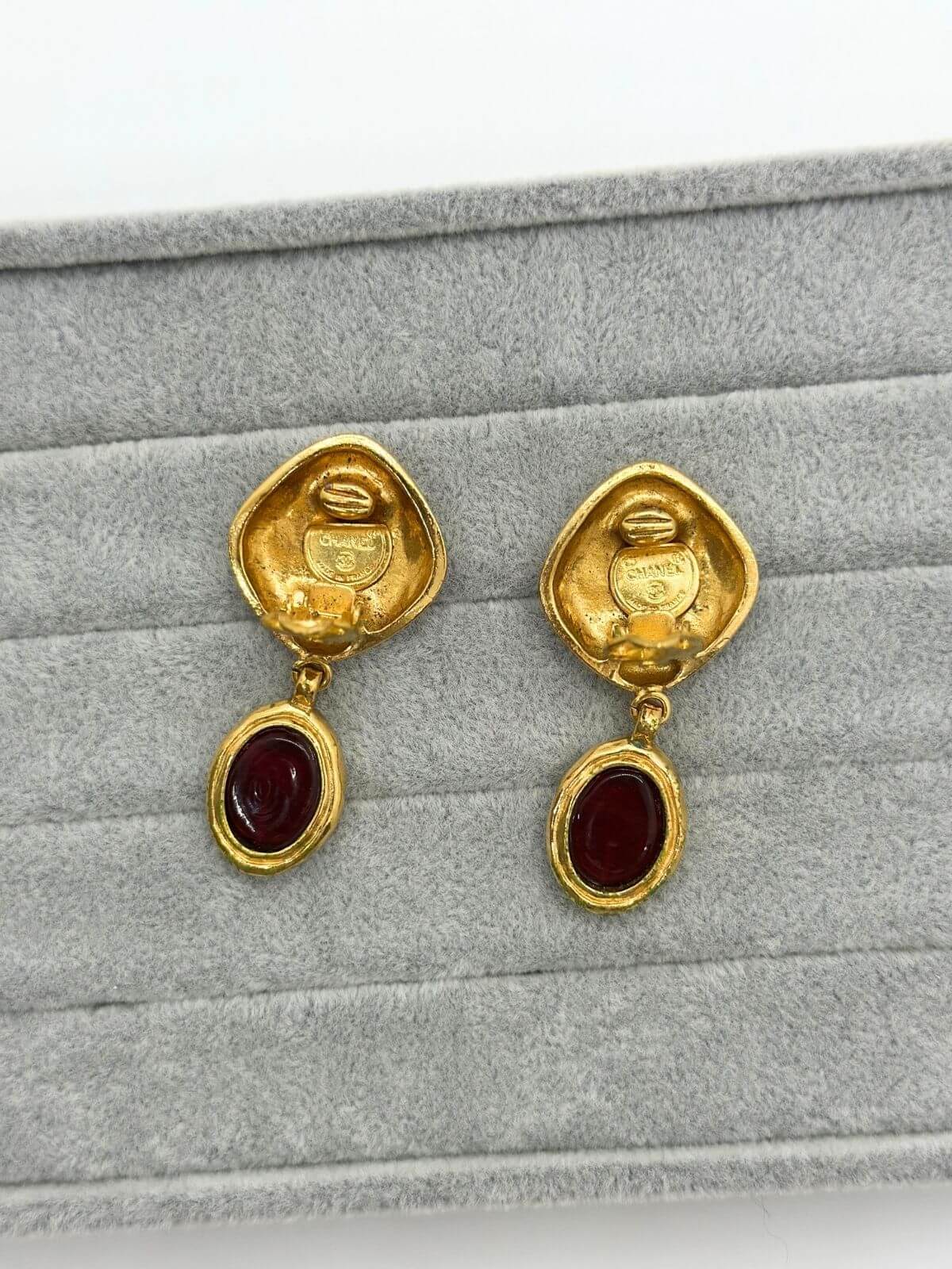 Chanel gold and red Gripoix earring on grey background. Showing signature.