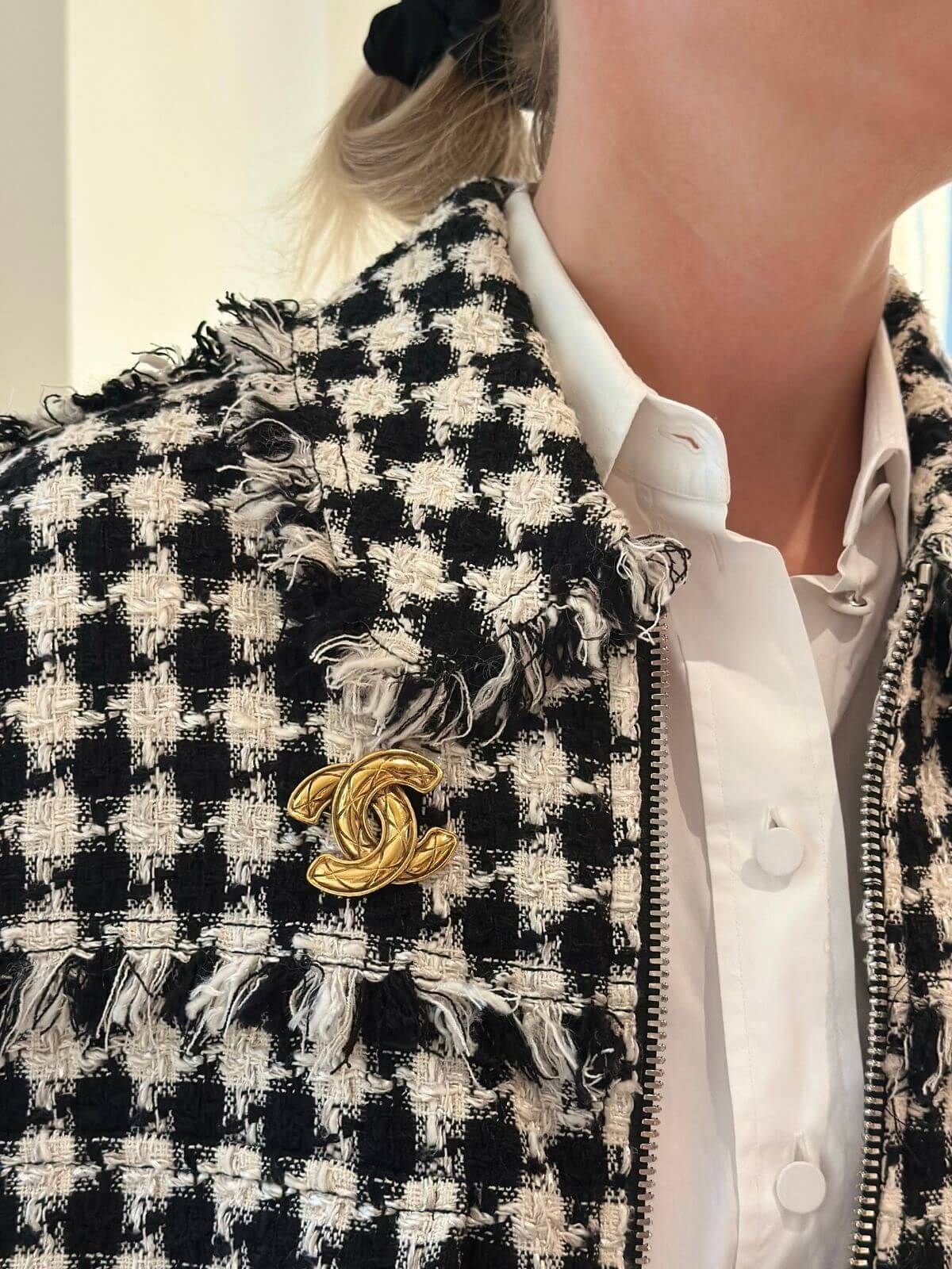 Model in black and white jacket wearing gold Chanel brooch.