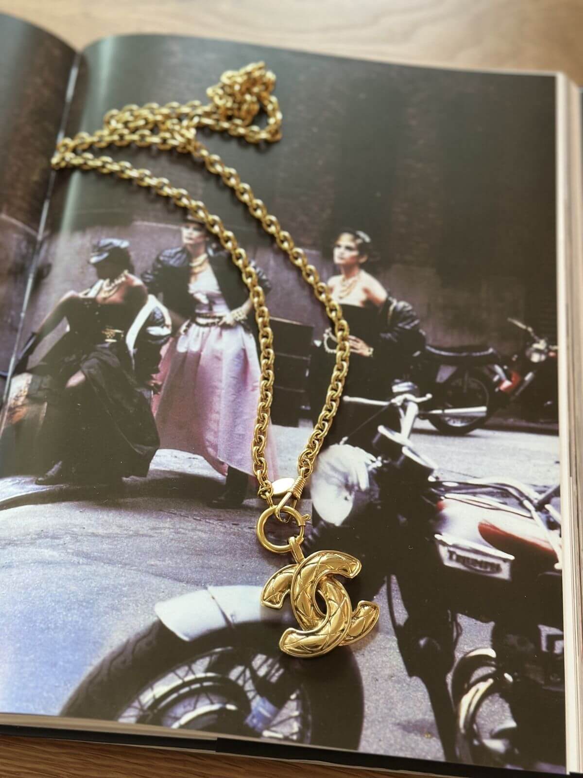 Gold necklace with a CC pendant on a magazine page
