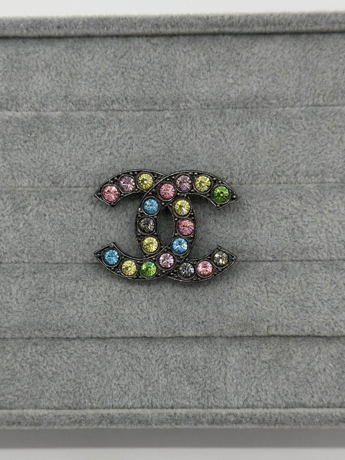 Pre-loved Chanel Multi color brooch on grey background