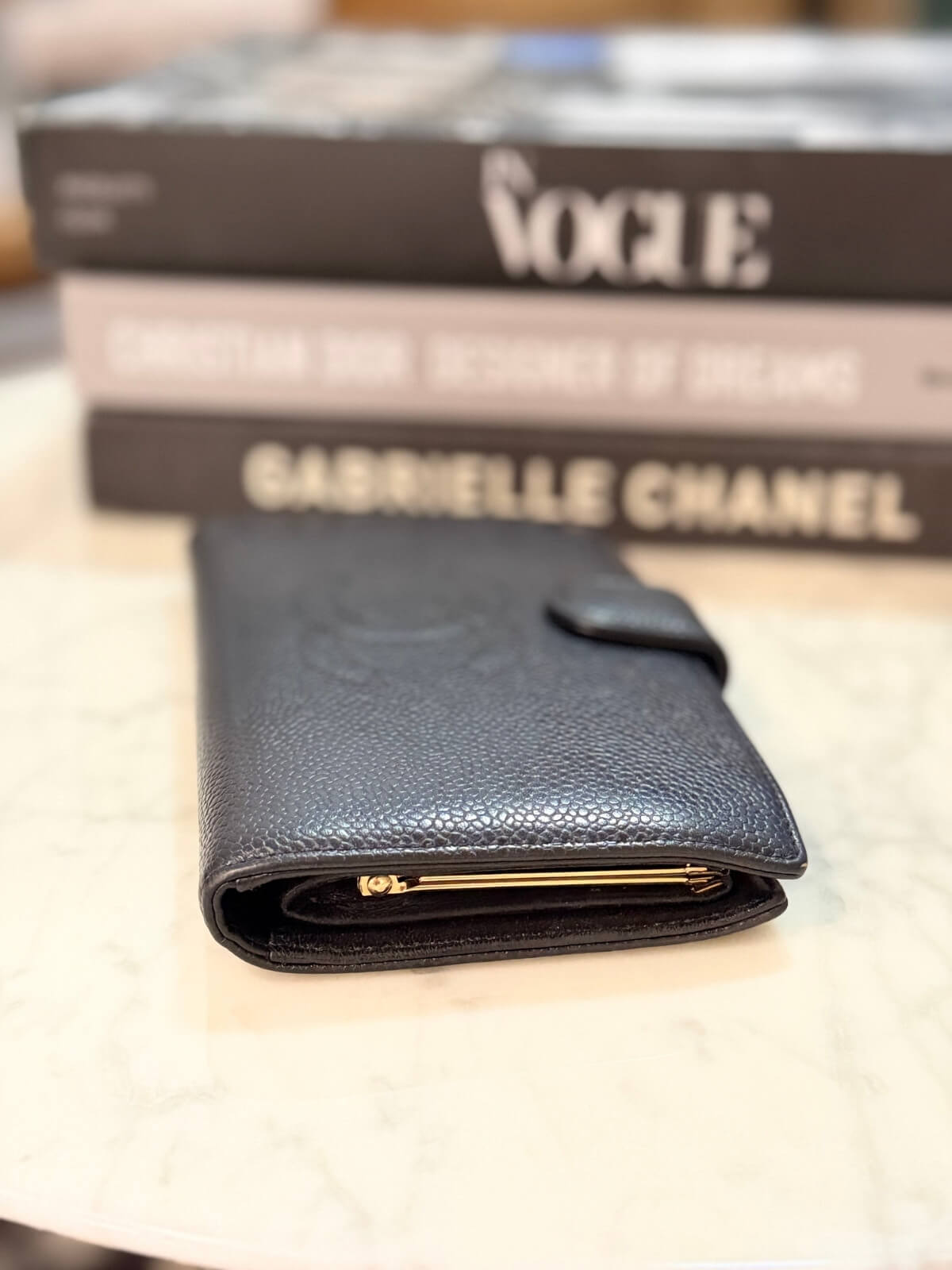 Louise Row featuring vintage Chanel black cavier embossed wallet on table