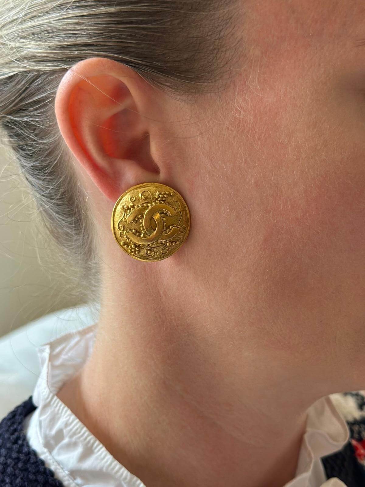 Model wearing gold Chanel pebble clip on earrings.