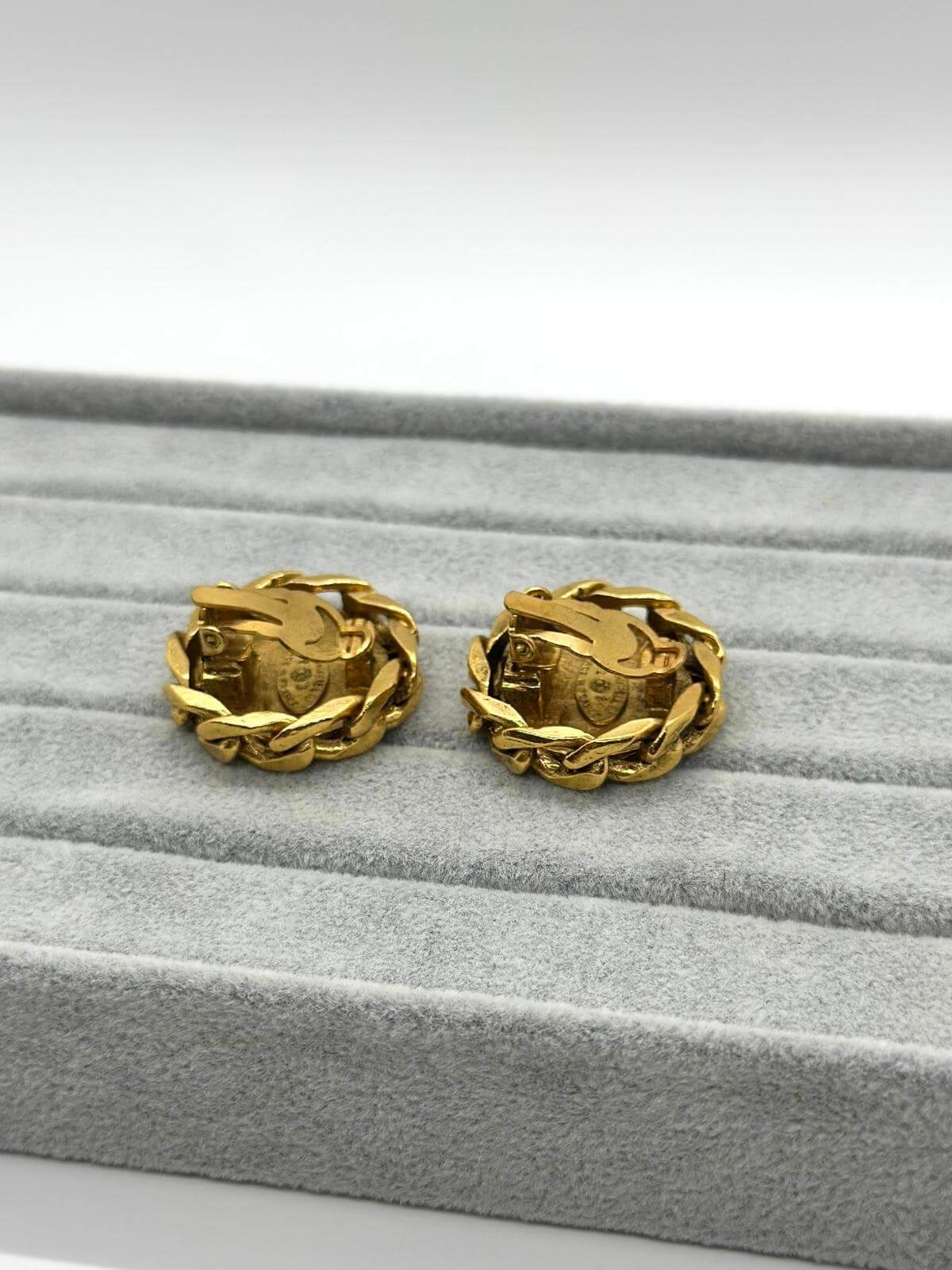 Chanel gold round clip on earring with crystal on grey and white background. Side view showing clips.