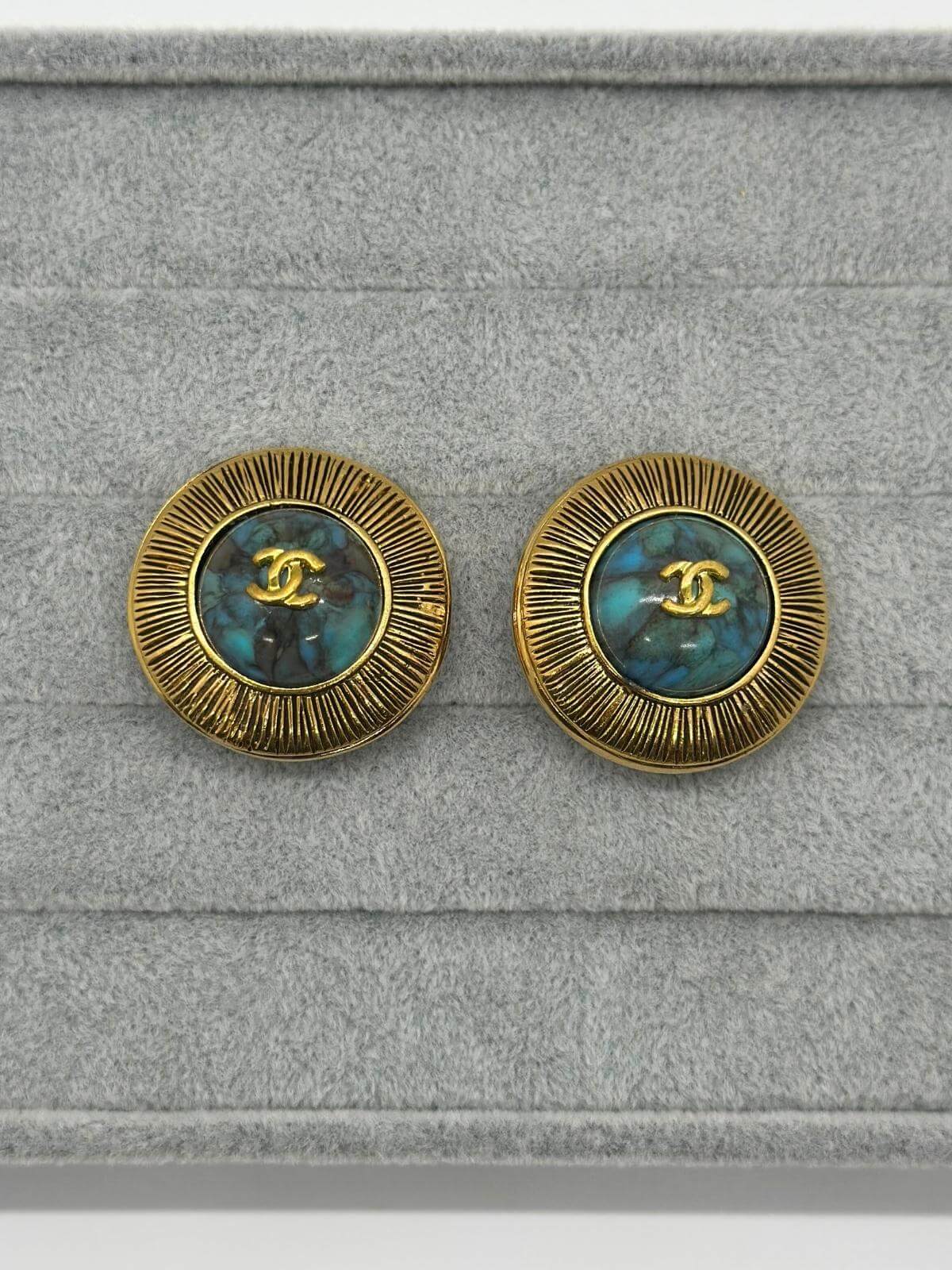 Chanel turquoise and gold vintage earrings on grey background.