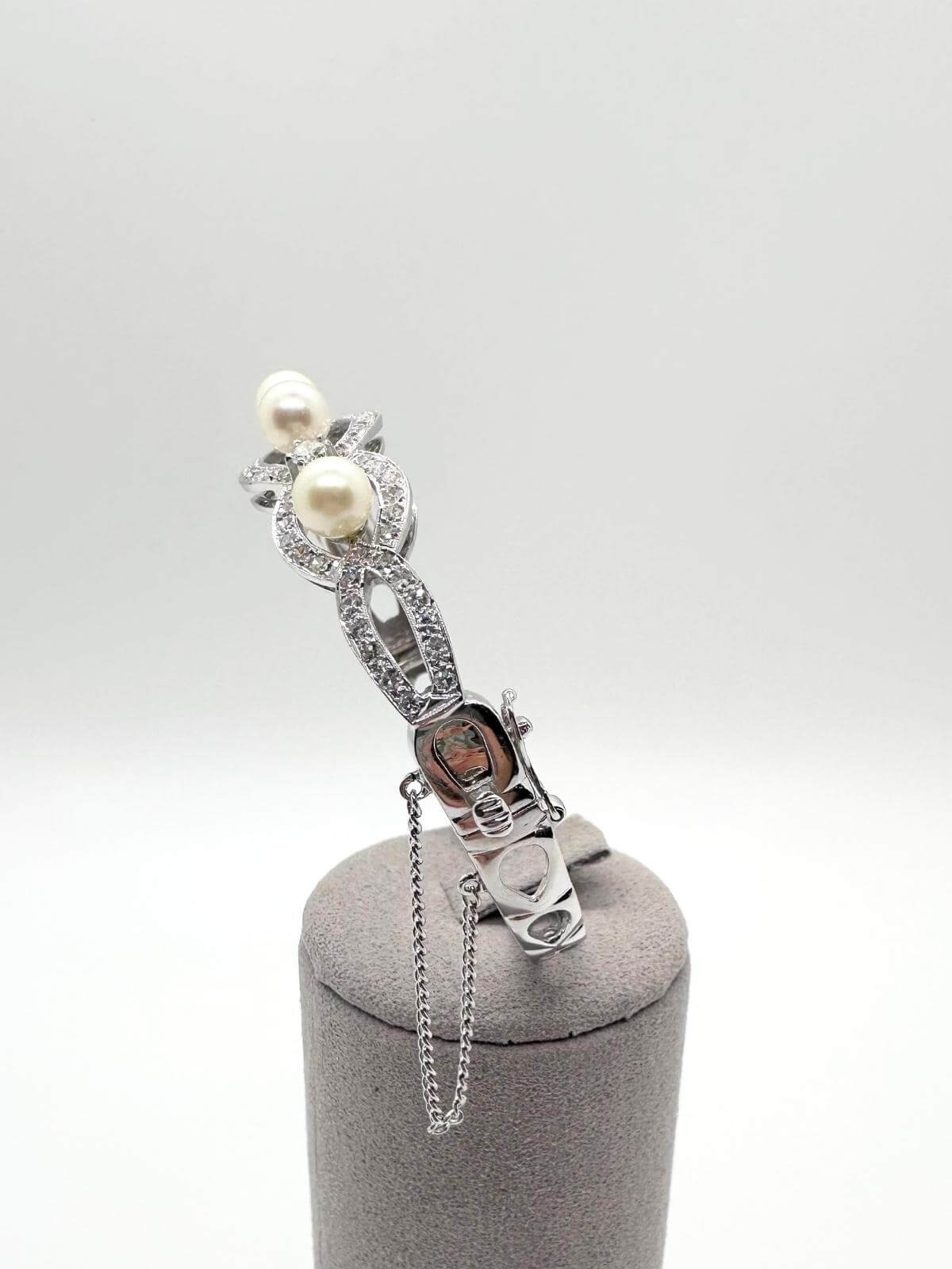 White gold and pearl bracelet on white background on grey fixture showing clasp