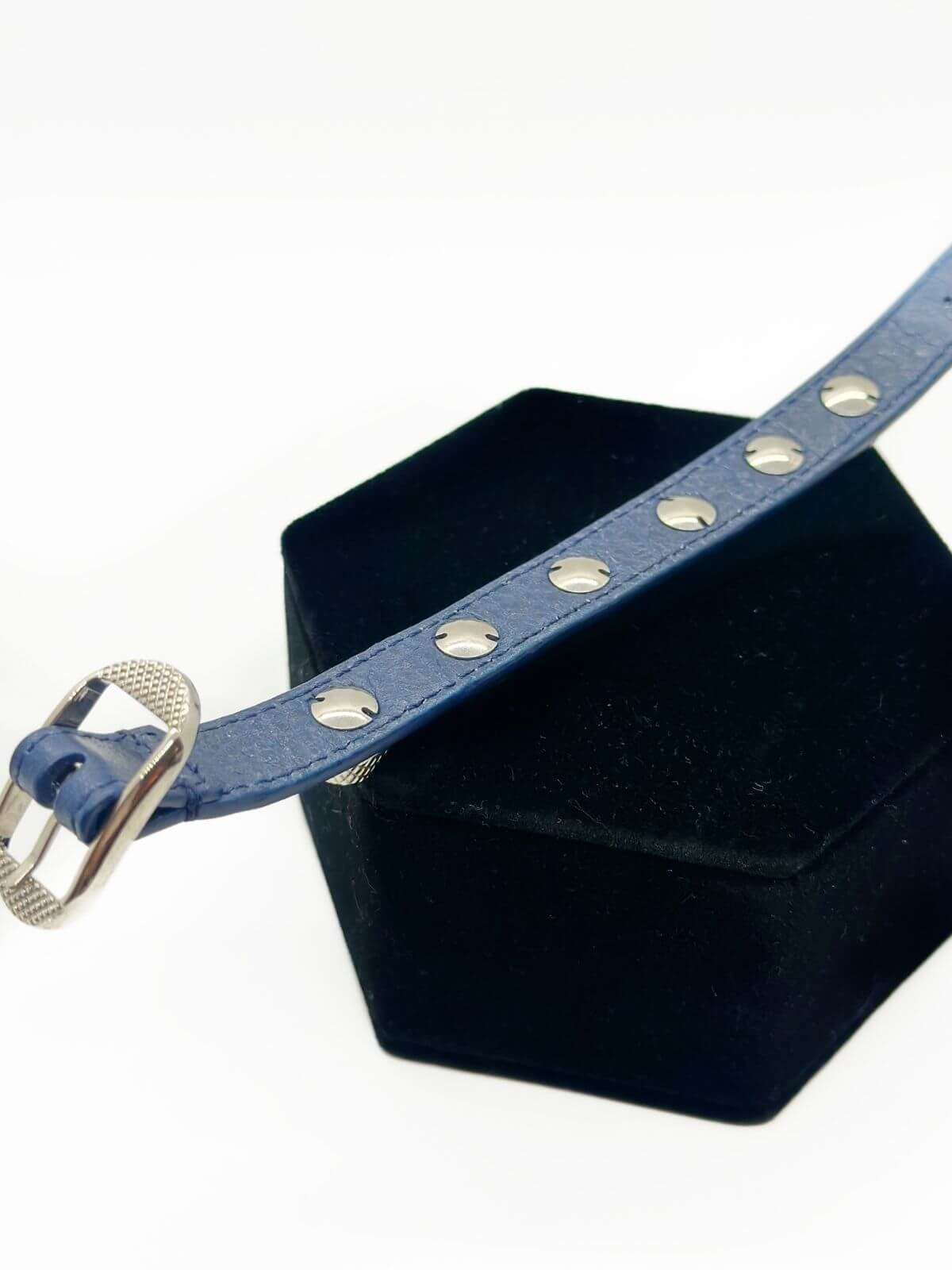 Back of Balenciaga studded leather bracelet on black fixture on white background.