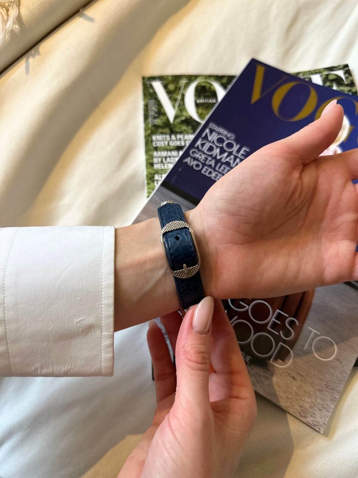 Hand wearing Balenciaga studded bracelet on a magazine background