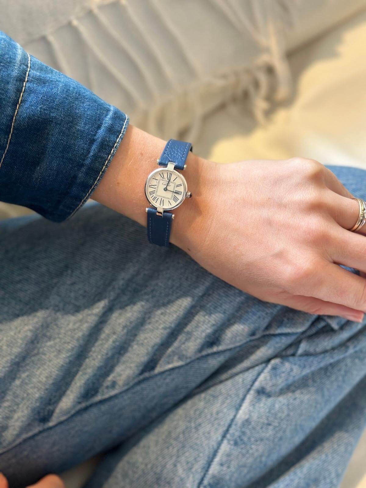 Model in jeans showing Cartier Vendome silver round watch.