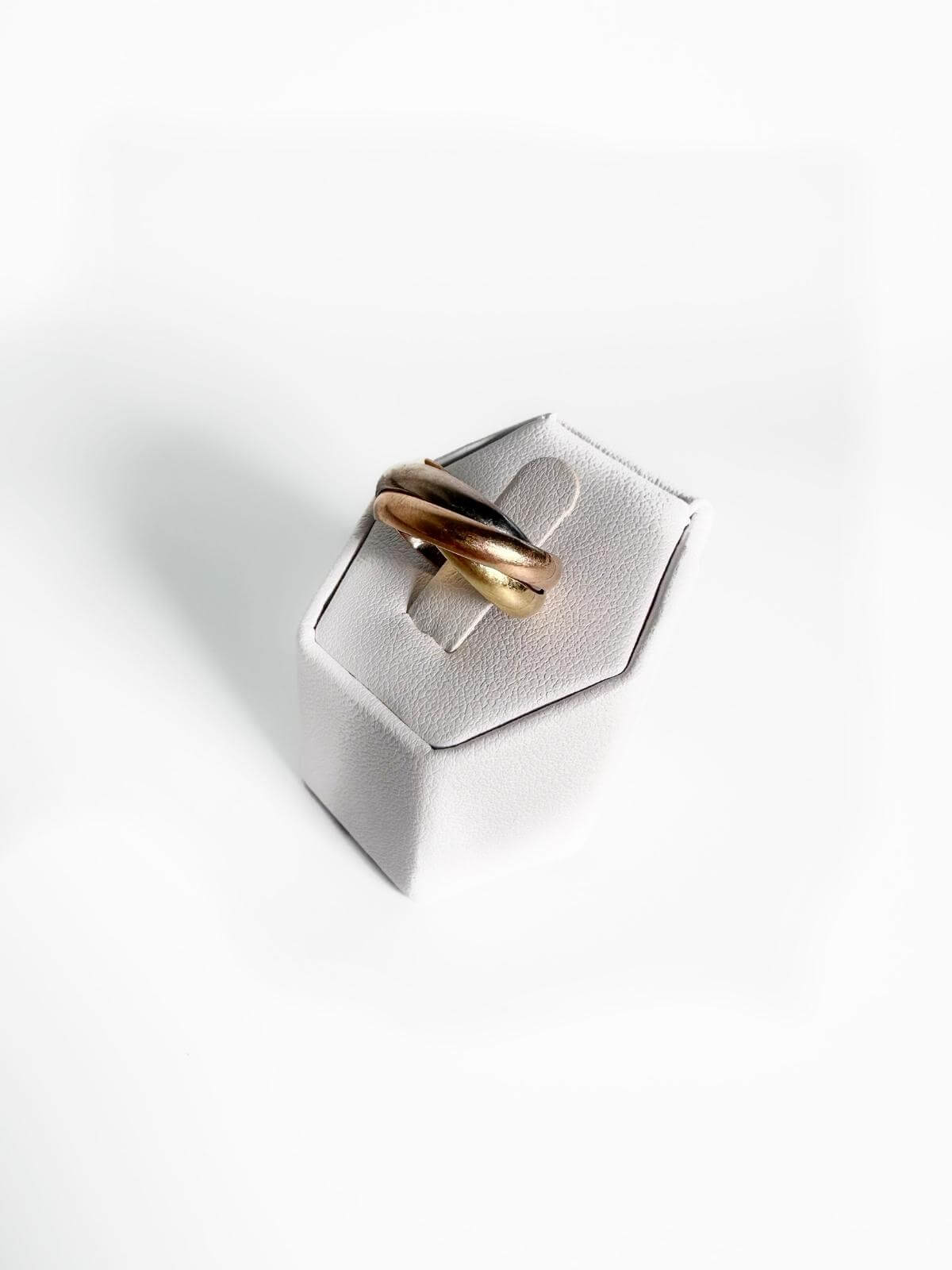 Cartier Gold ring on a silver hexagonal stand against a white background