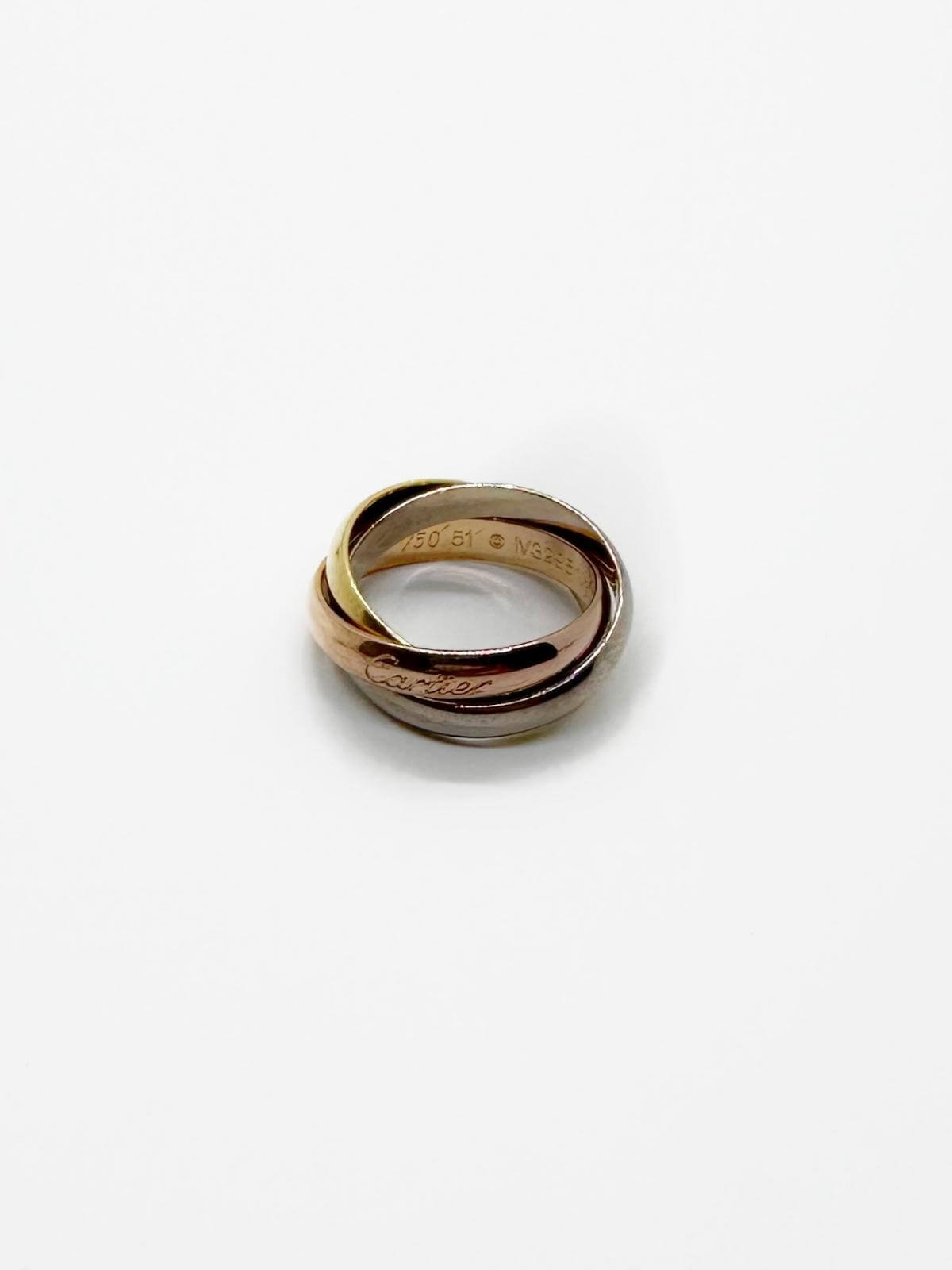 Three gold rings stacked on a white background Cartier Trinity ring