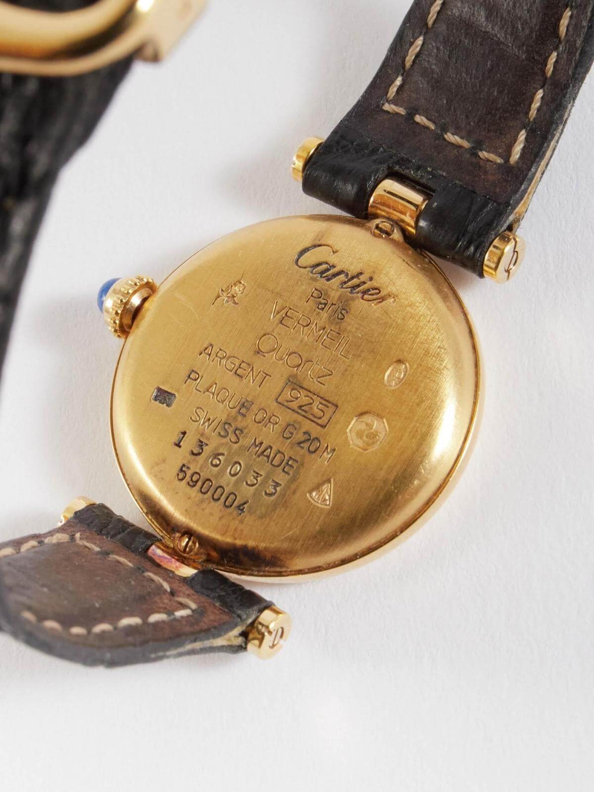 Back view Close-up of a Cartier watch with gold case and brown leather strap on a white background
