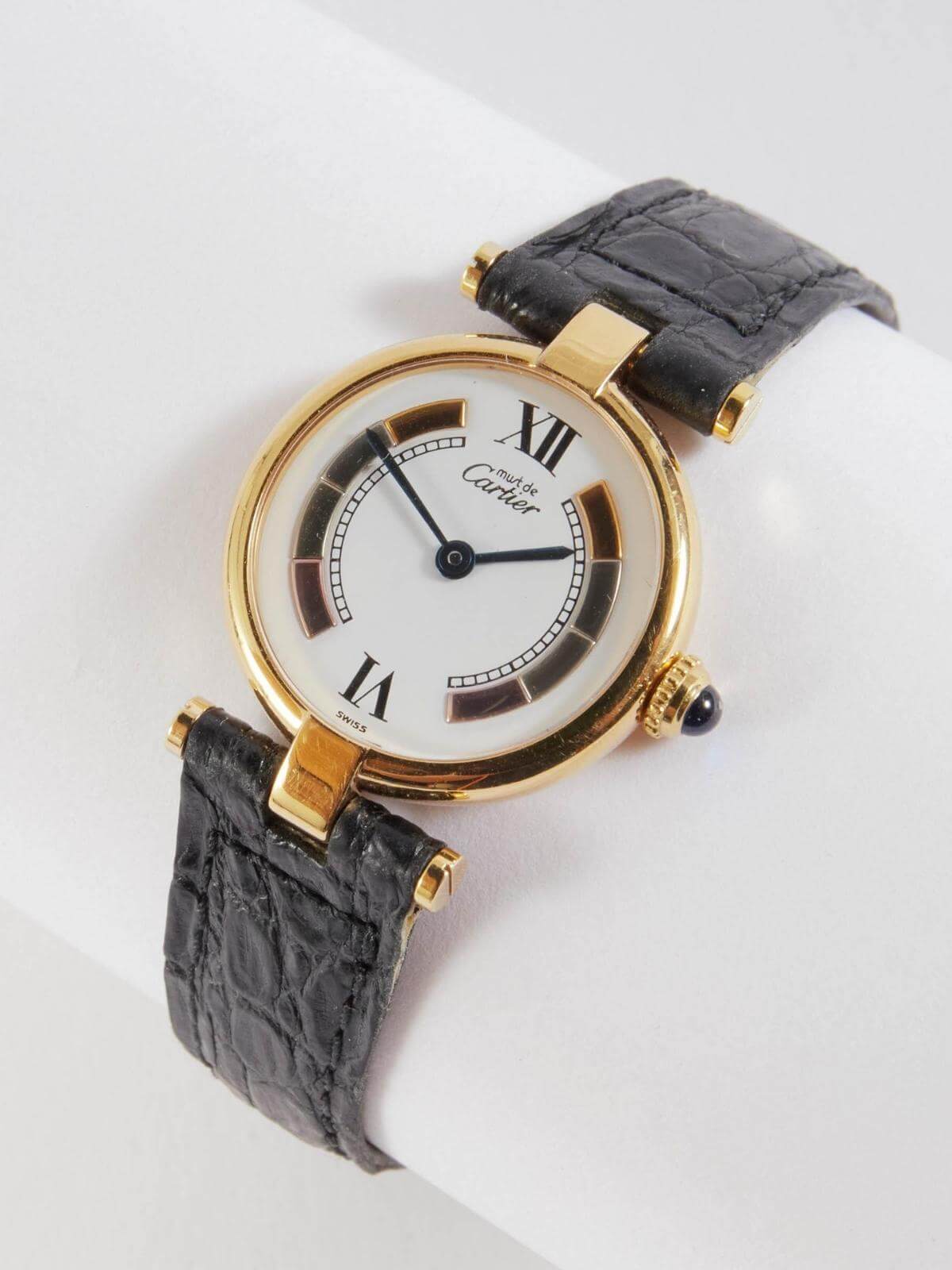 Cartier gold round face watch with black strap on white background
