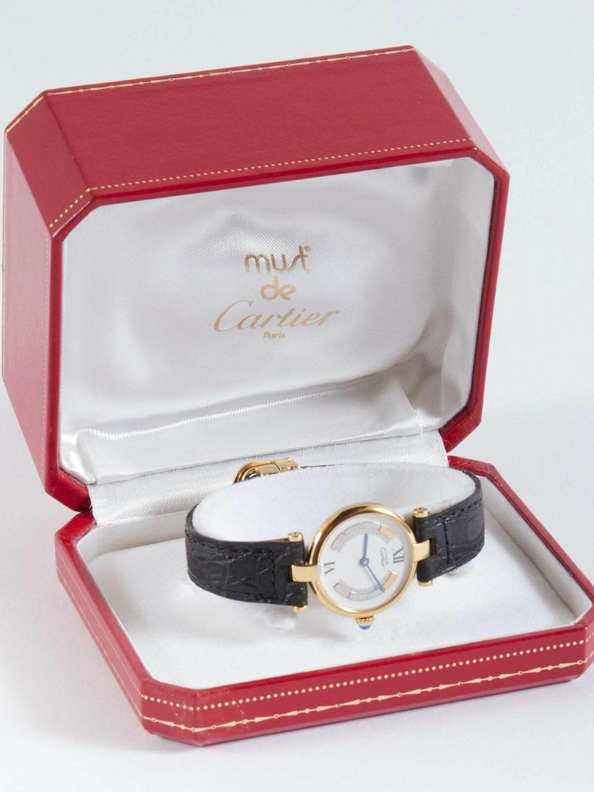 Cartier De Must watch with black strap in a red Cartier box on white background