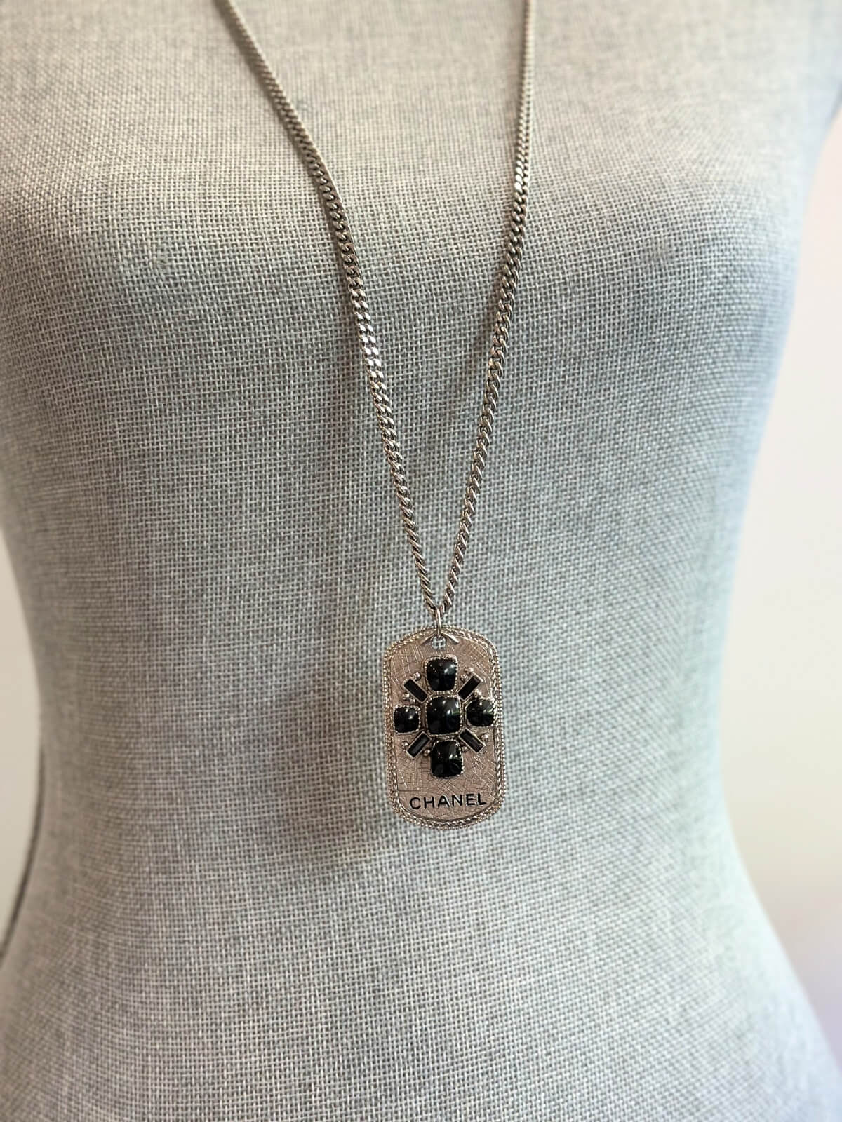 Louise Row Studio featuring Chanel long silver necklace with dog tag made with enamel design and CHANEL markings on body form.
