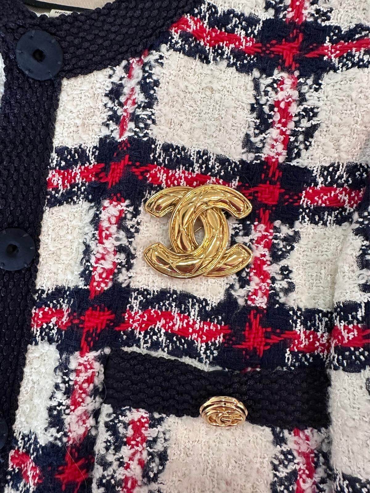 Gold Chanel CC brooch on plaid jacket