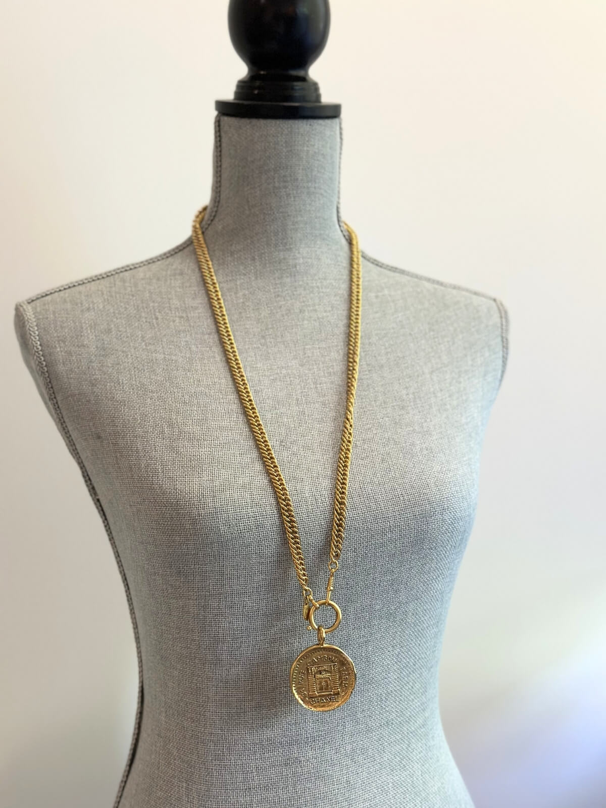 Louise Row Studio featuring vintage Chanel rue de Cambon gold necklace with long chain and medallion on grey body form. 