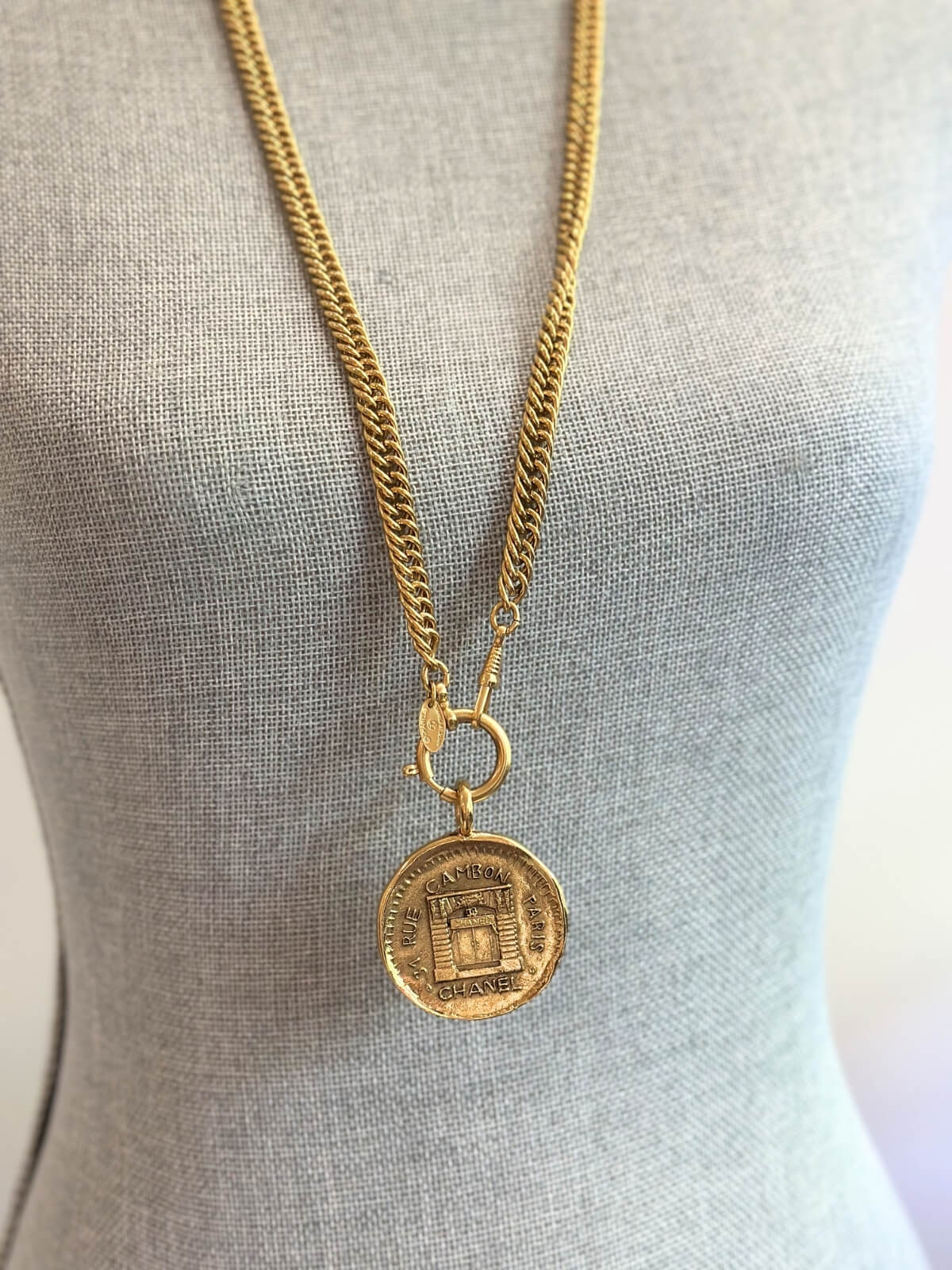Louise Row Studio featuring vintage Chanel rue de Cambon gold necklace with long chain and medallion on grey body form. 