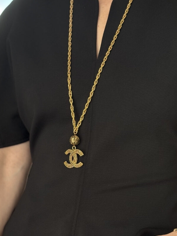 Lousie Row Studio featuring Model in black shirt wearing long Chanel gold CC necklace. 