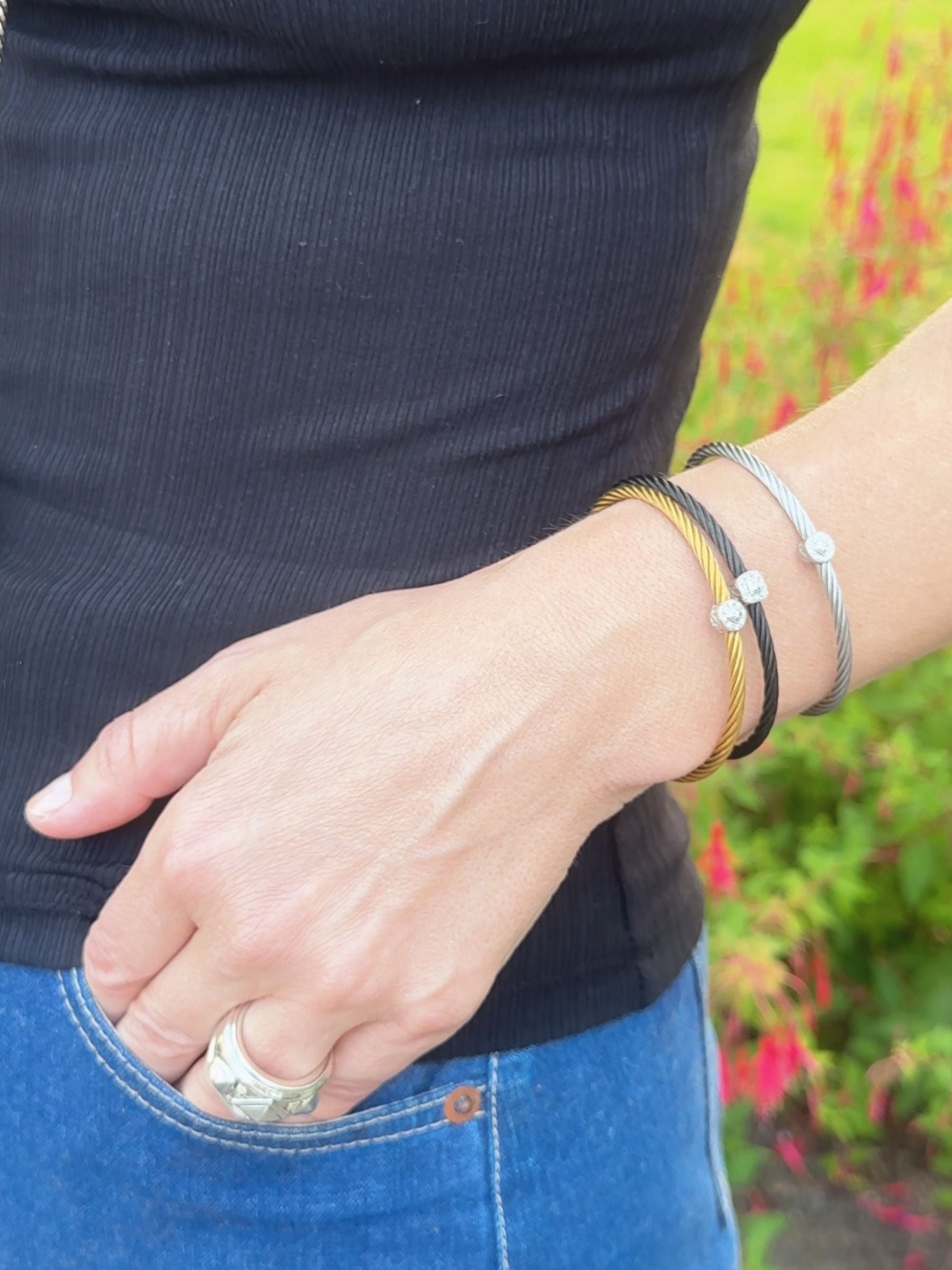 Louise row studio featuring model's arm wearing three Charriol bracelets in gold, silver and black with hand in pocket. 