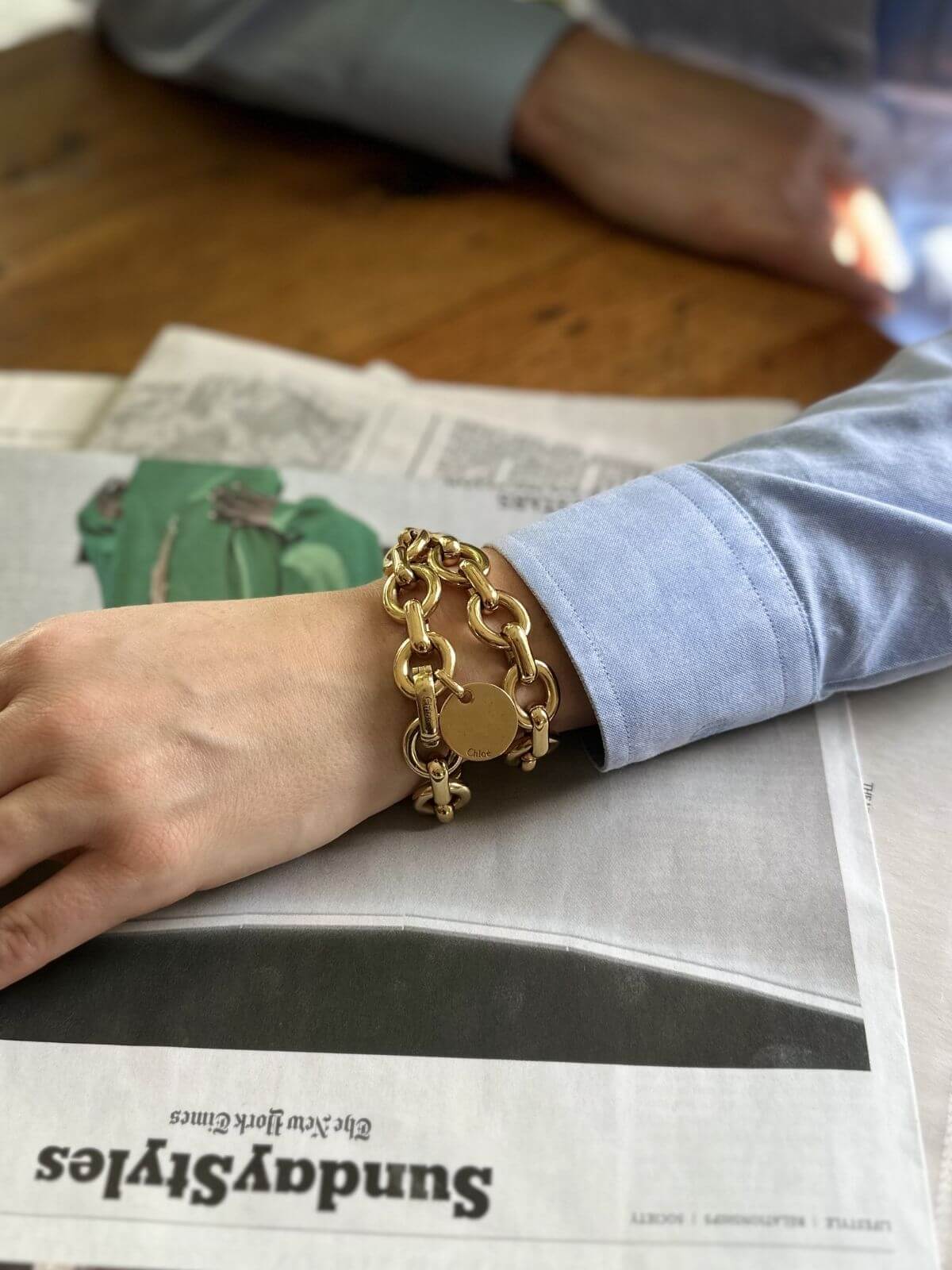 Gold chain bracelet on a person's wrist with a blurred background