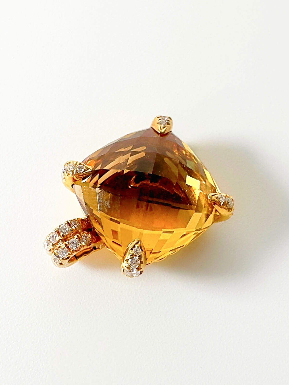 Gold pendant with prong settings set with diamonds with a Citrine gemstone on a white background