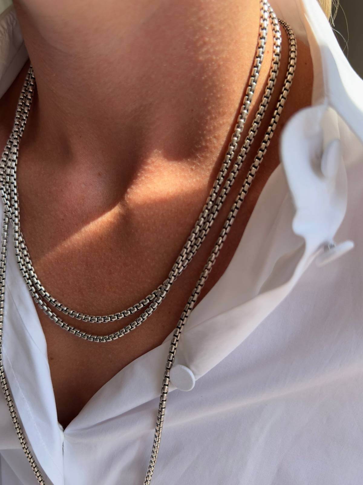 Model close up in white shirt wearing DY silver chain wrapped long around her neck