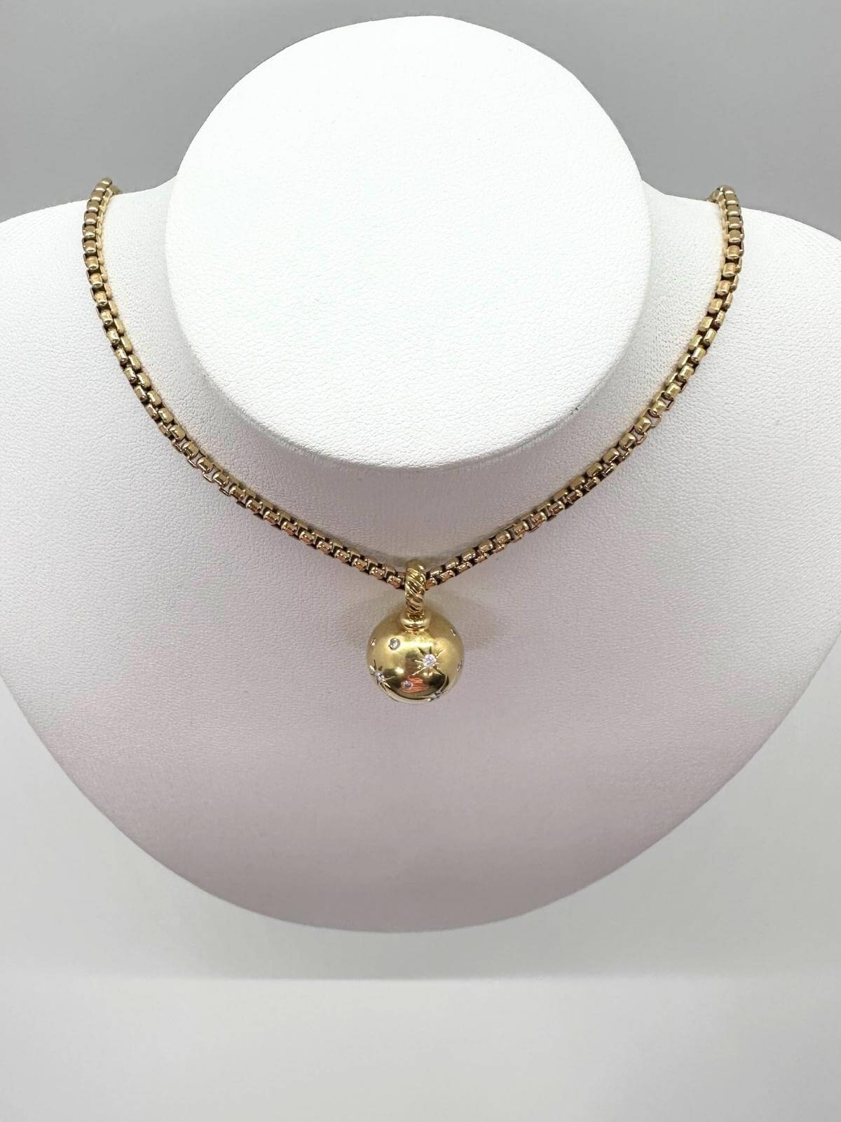 Gold necklace with a pendant on a mannequin bust against a gray background