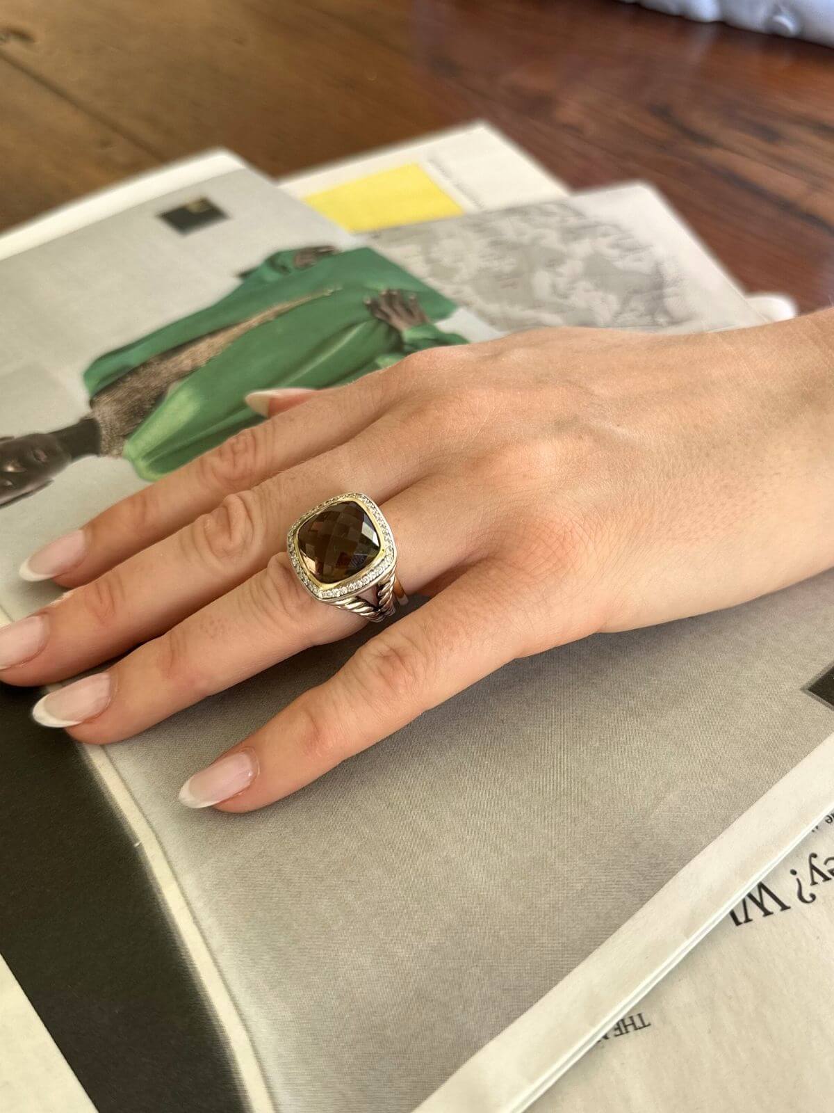 Hand wearing a ring with a dark stone on a book