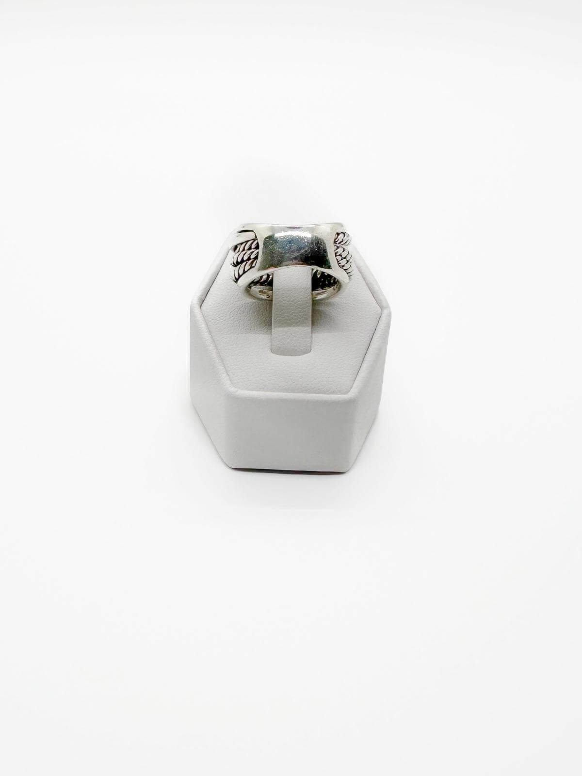 Silver ring on a white stand against a white background