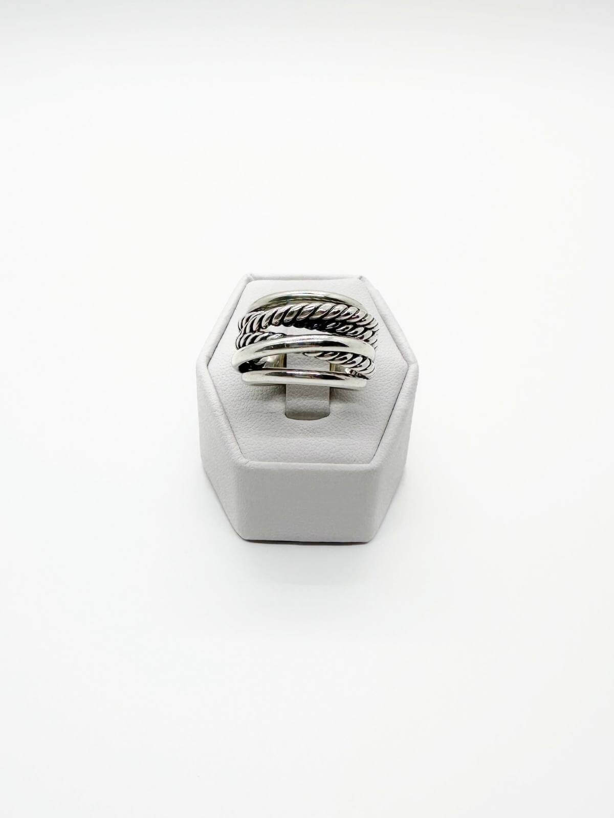 David Yurman Silver ring with textured band on a white stand against a white background