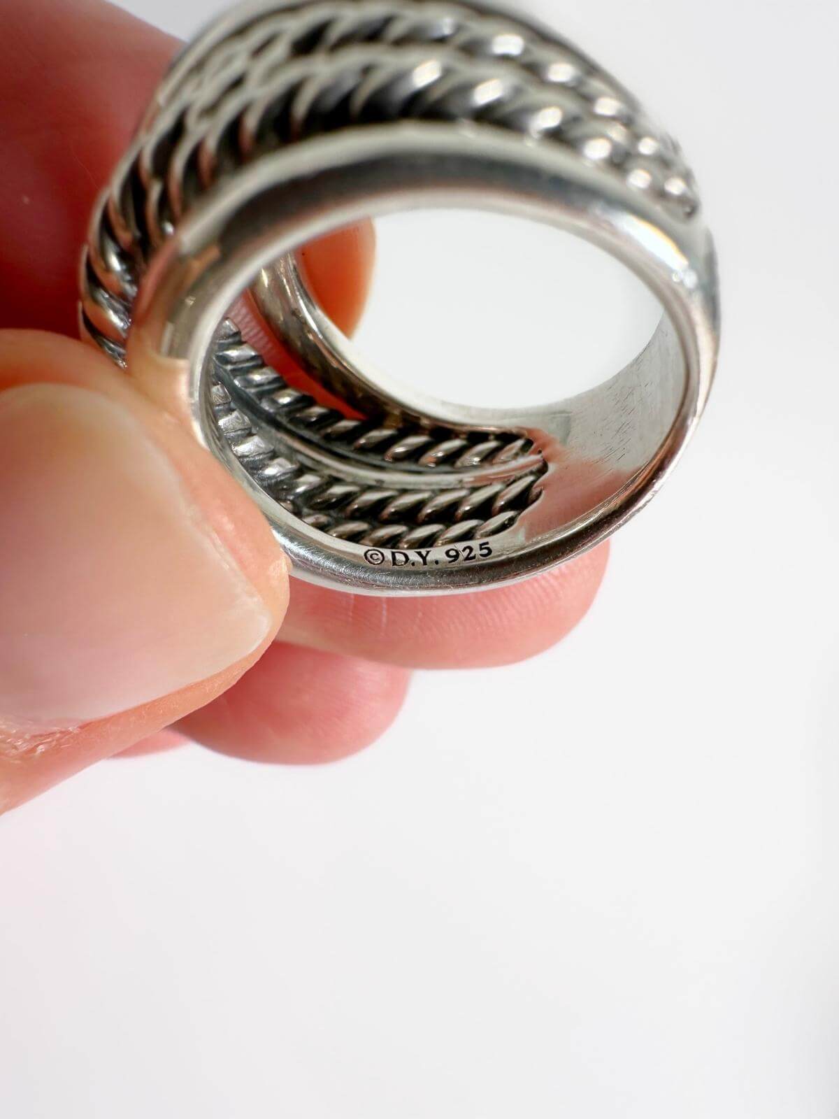 hand holding DY crossover ring with signature DY 925 stamp