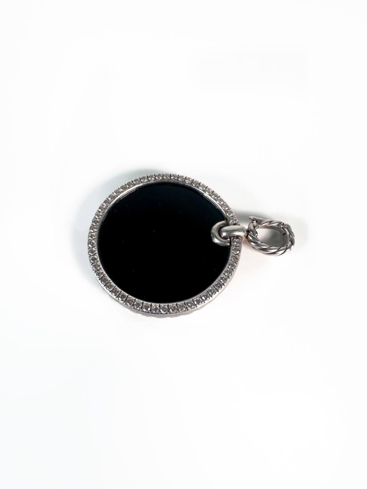 SIde view of Silver pendant with diamond bezel with center stone black onyx on white background