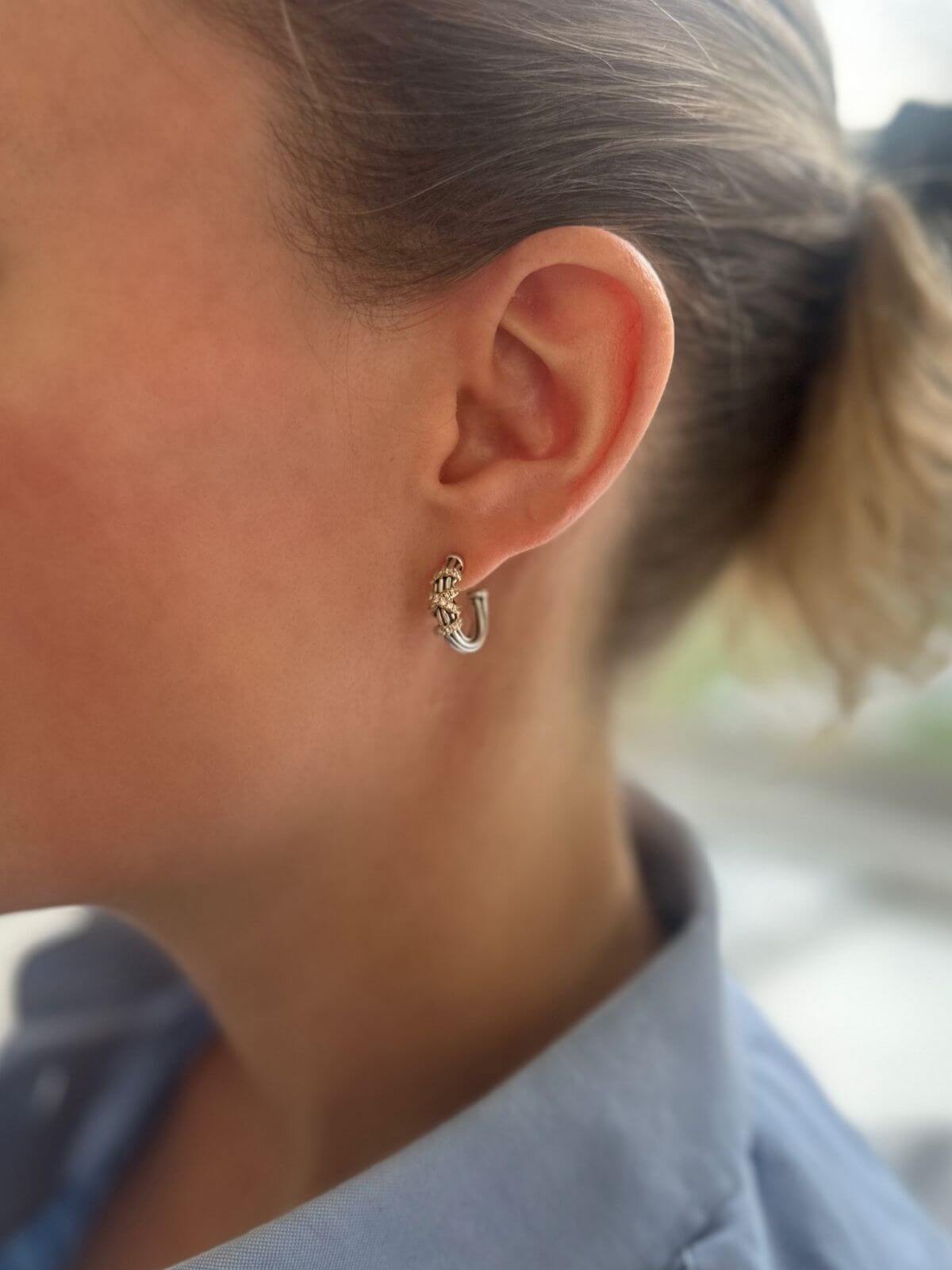 Close-up of a person wearing a small hoop earring with a blurred background